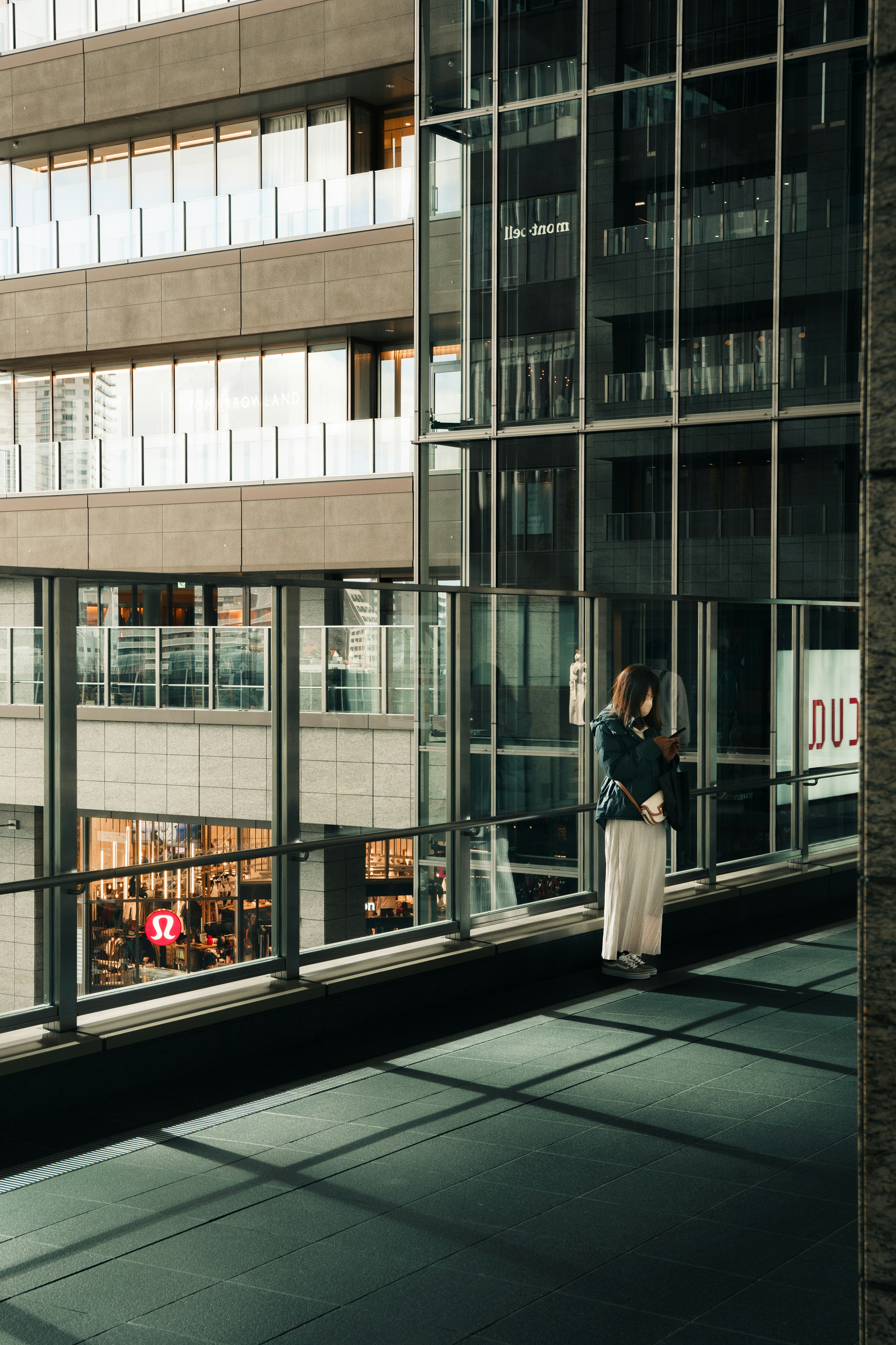 Une femme debout sur un balcon en verre d'un bâtiment moderne