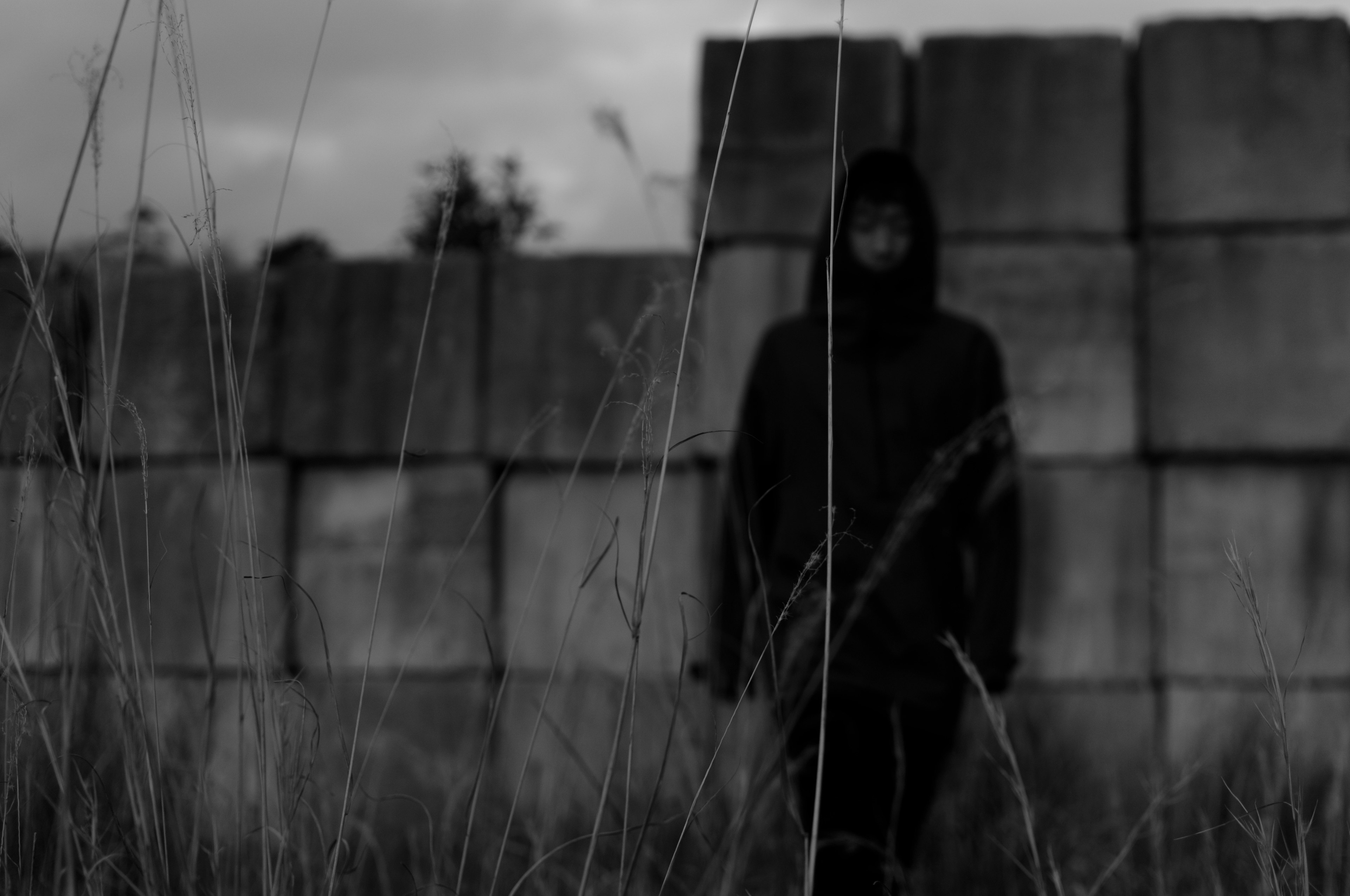 Una figura de pie en un entorno oscuro junto a una pared de bloques de concreto