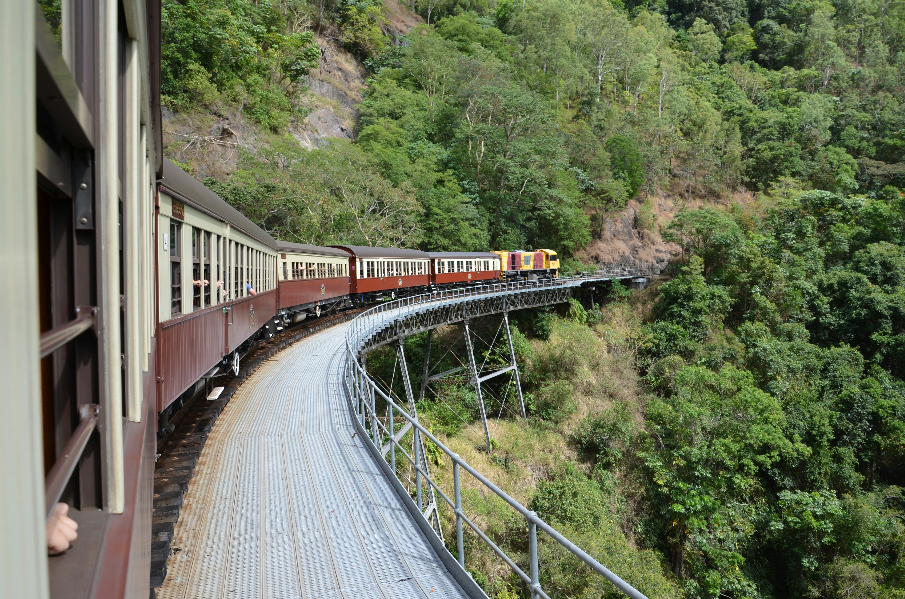 Jalur kereta melengkung dengan kereta yang melewati gunung hijau