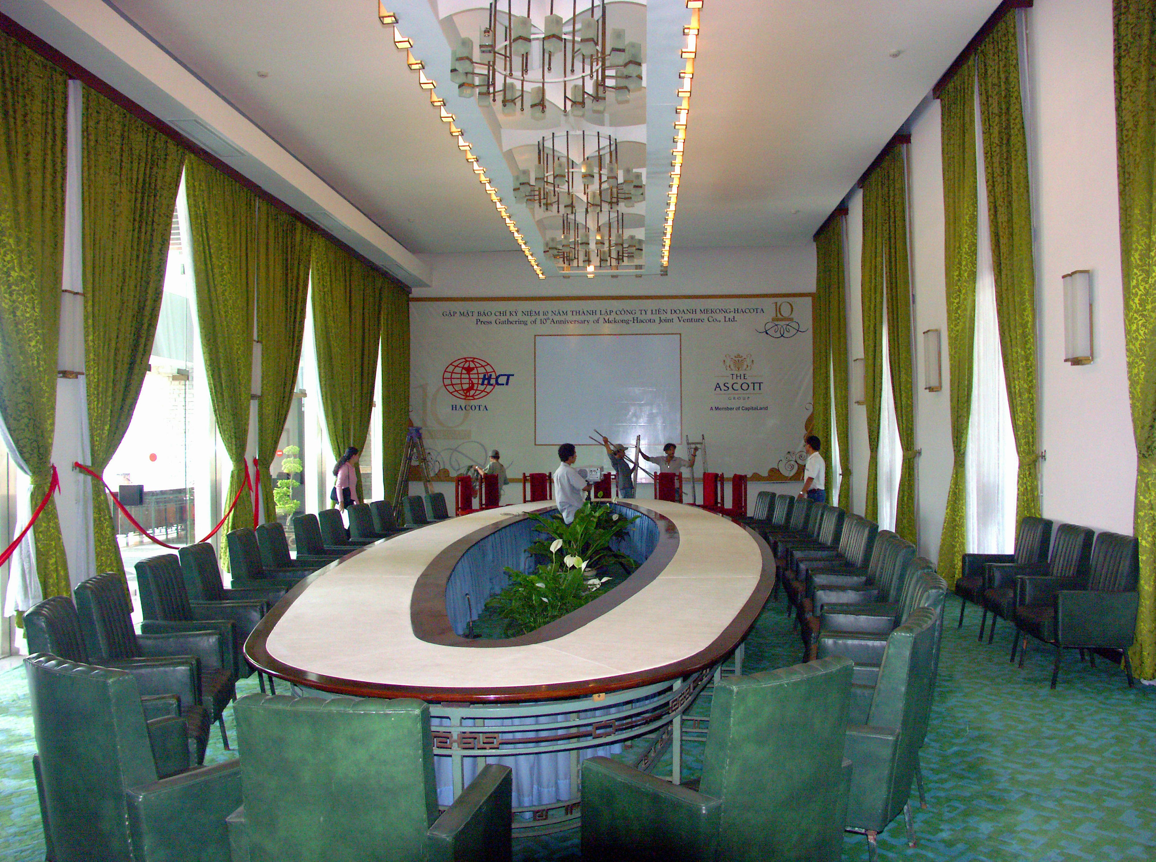 Sala de conferencias con cortinas verdes y una lámpara de araña