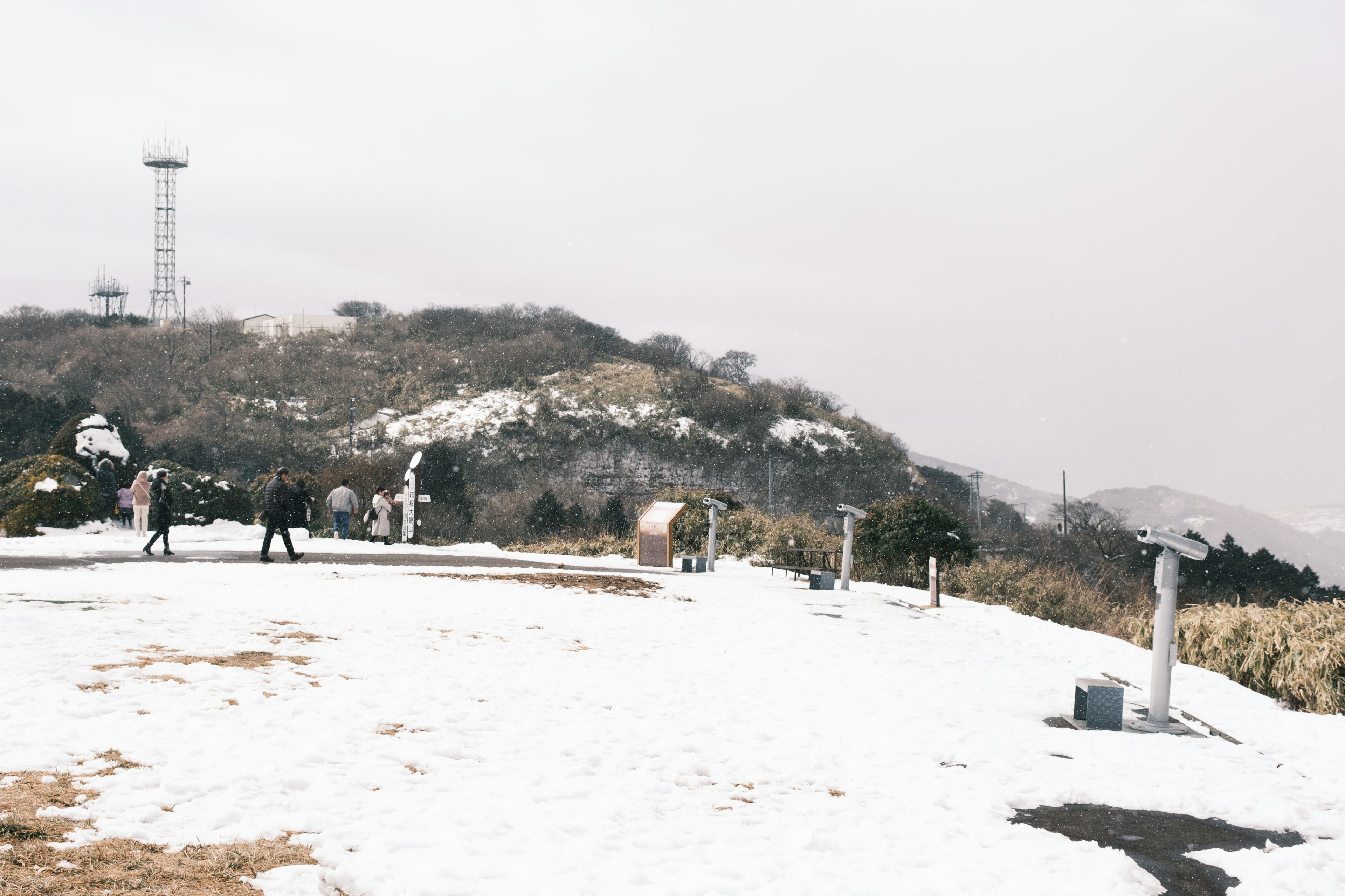 Schneebedeckte Landschaft mit Menschen, die auf einem Hügel spazieren