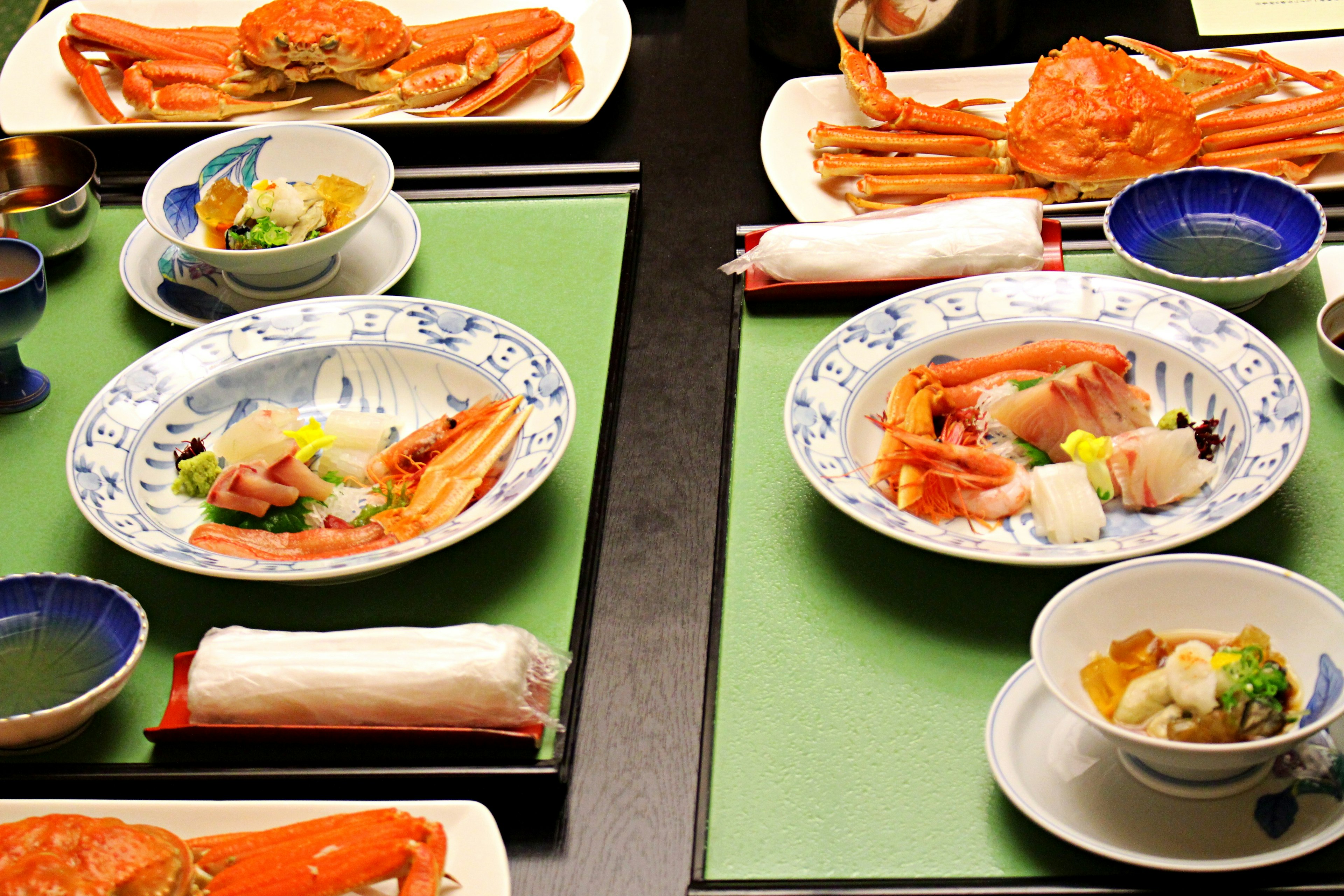 Mise en place de fruits de mer luxueux avec des crabes et du sashimi sur des assiettes avec des nappes vertes