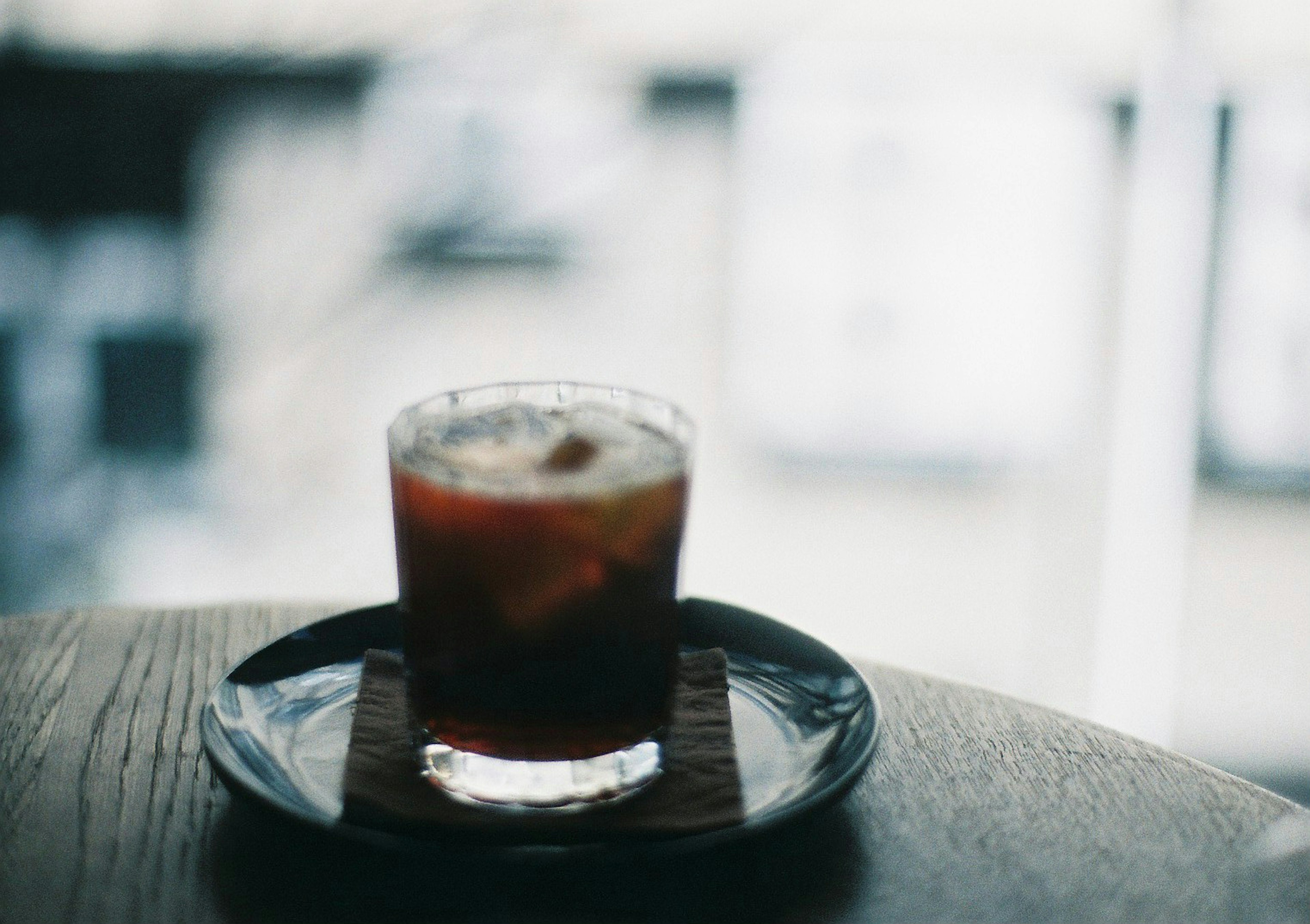 Cocktail glass placed on a dark wooden table with ice and fruit visible