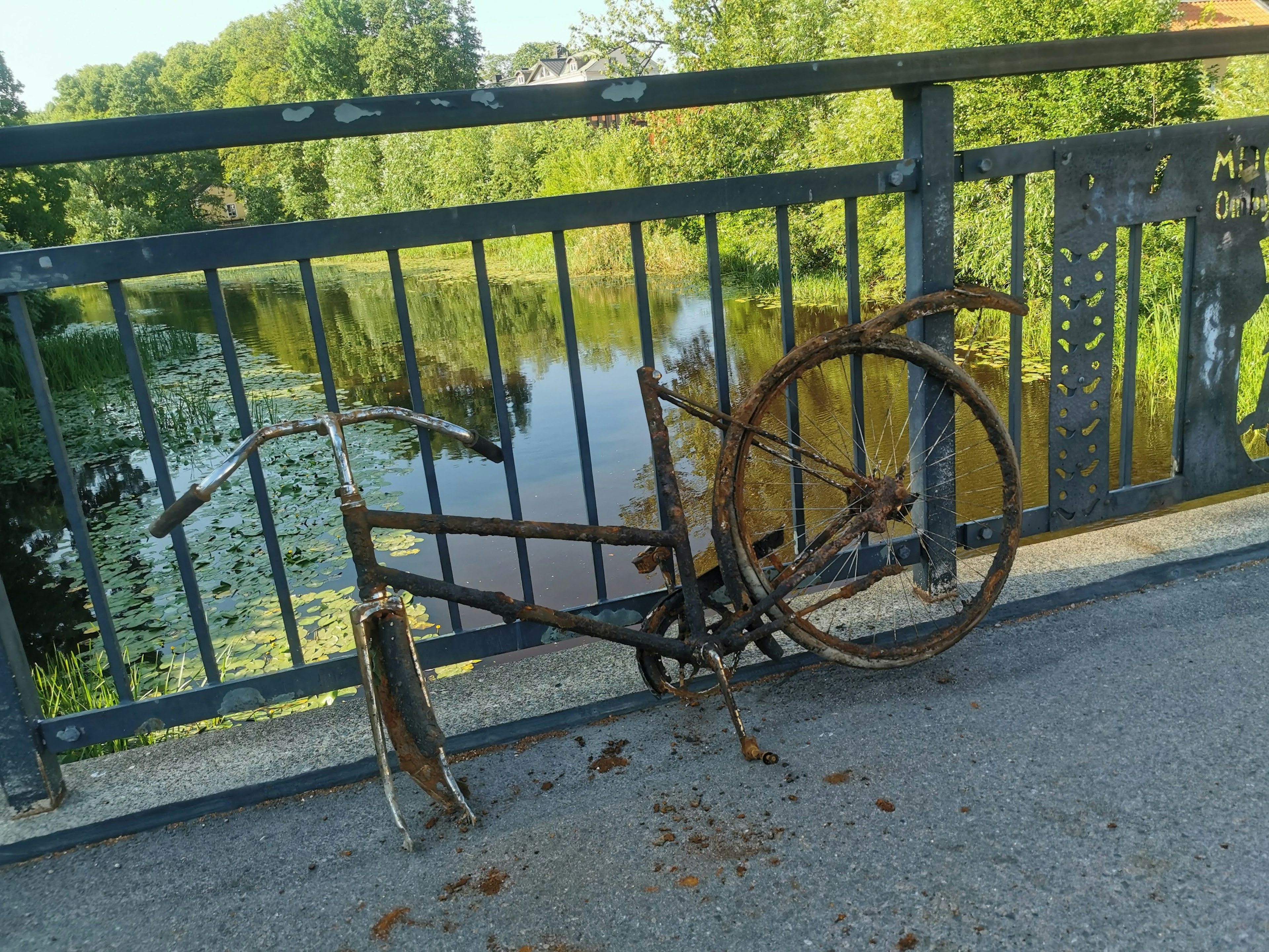 Rusty bicycle resting on a bridge overlooking a river