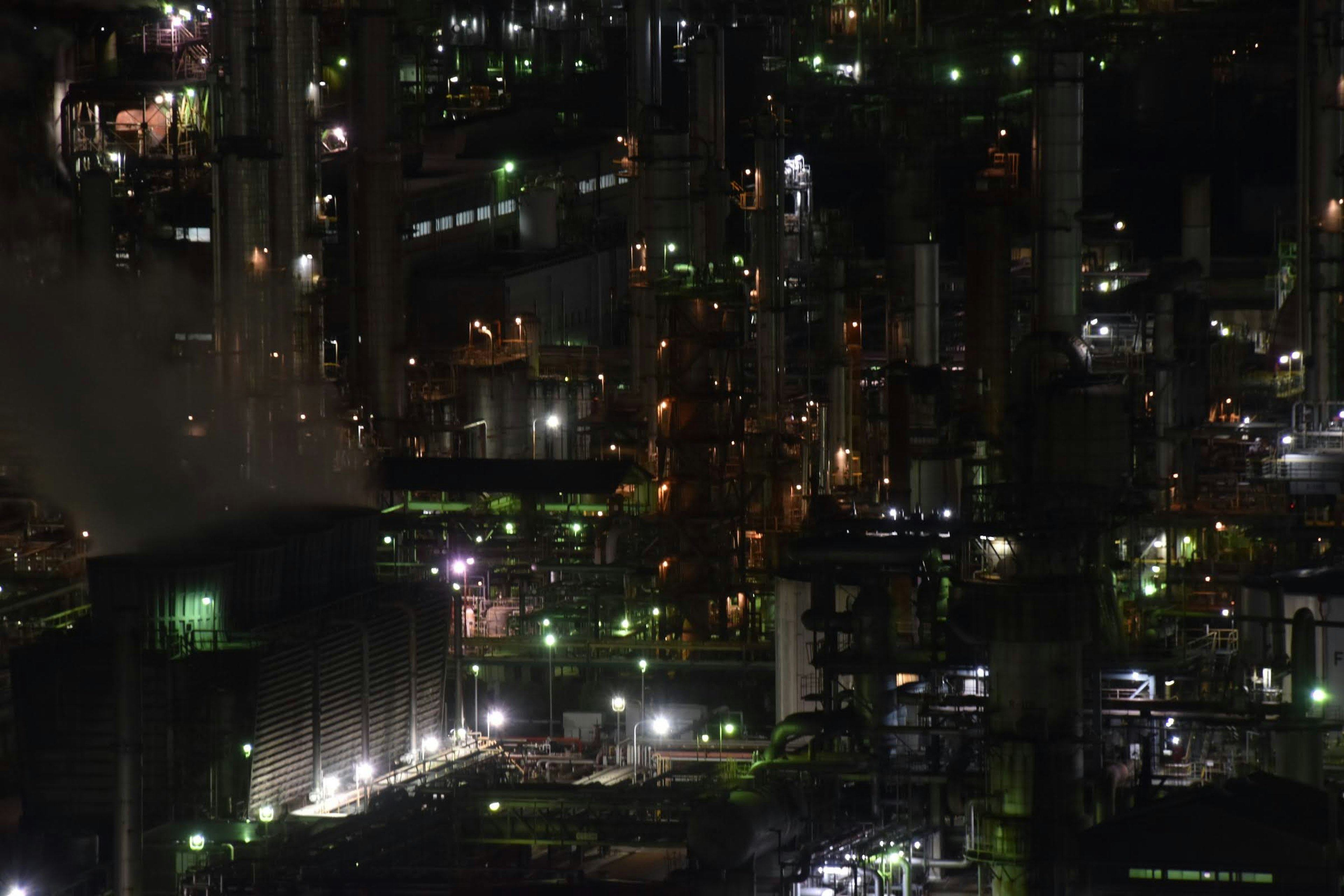 Nachtsicht auf ein Industriegebiet mit hohen Schornsteinen und vielen Lichtern