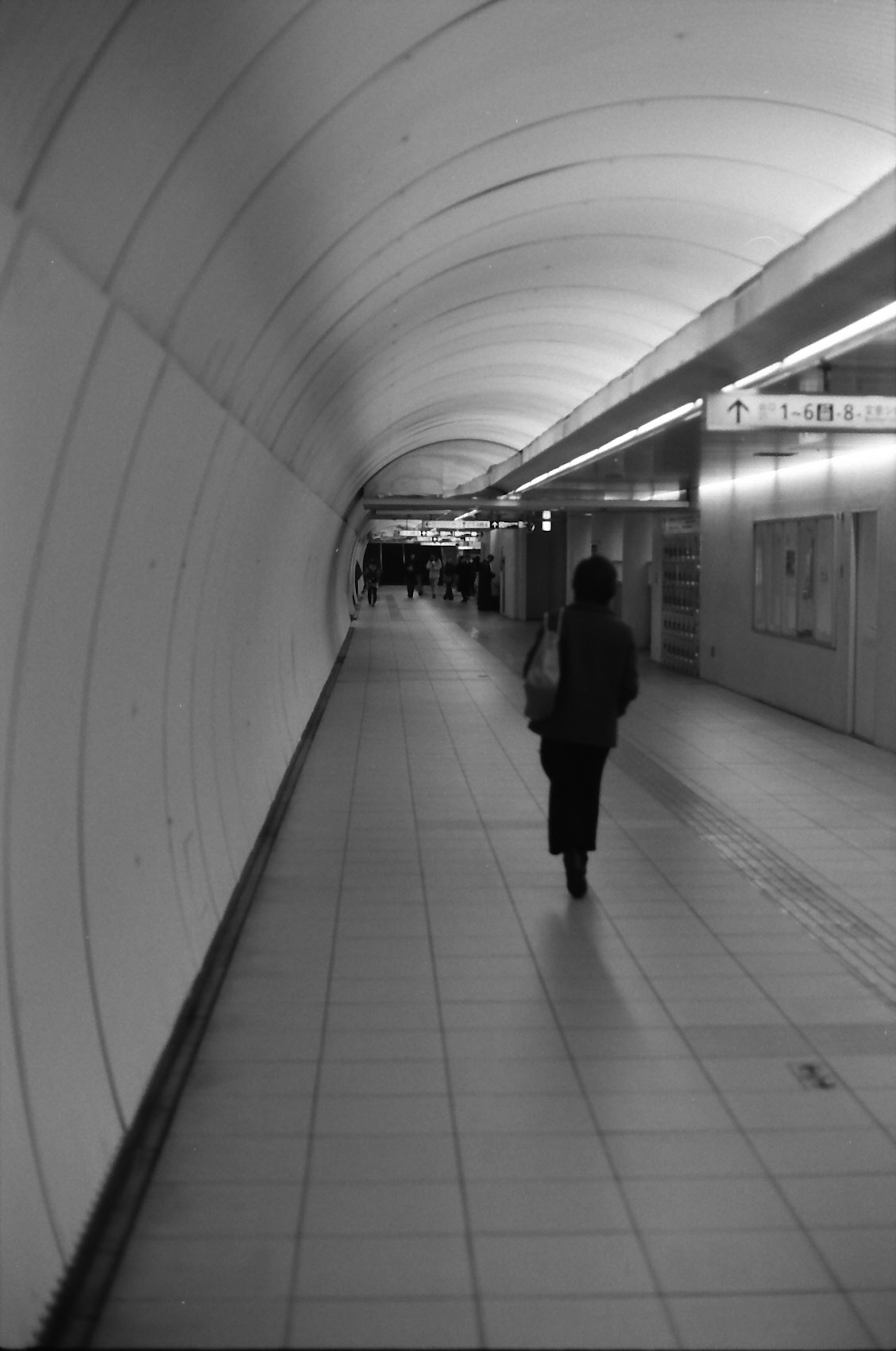 Monochrome photo of a person walking in an underground passage