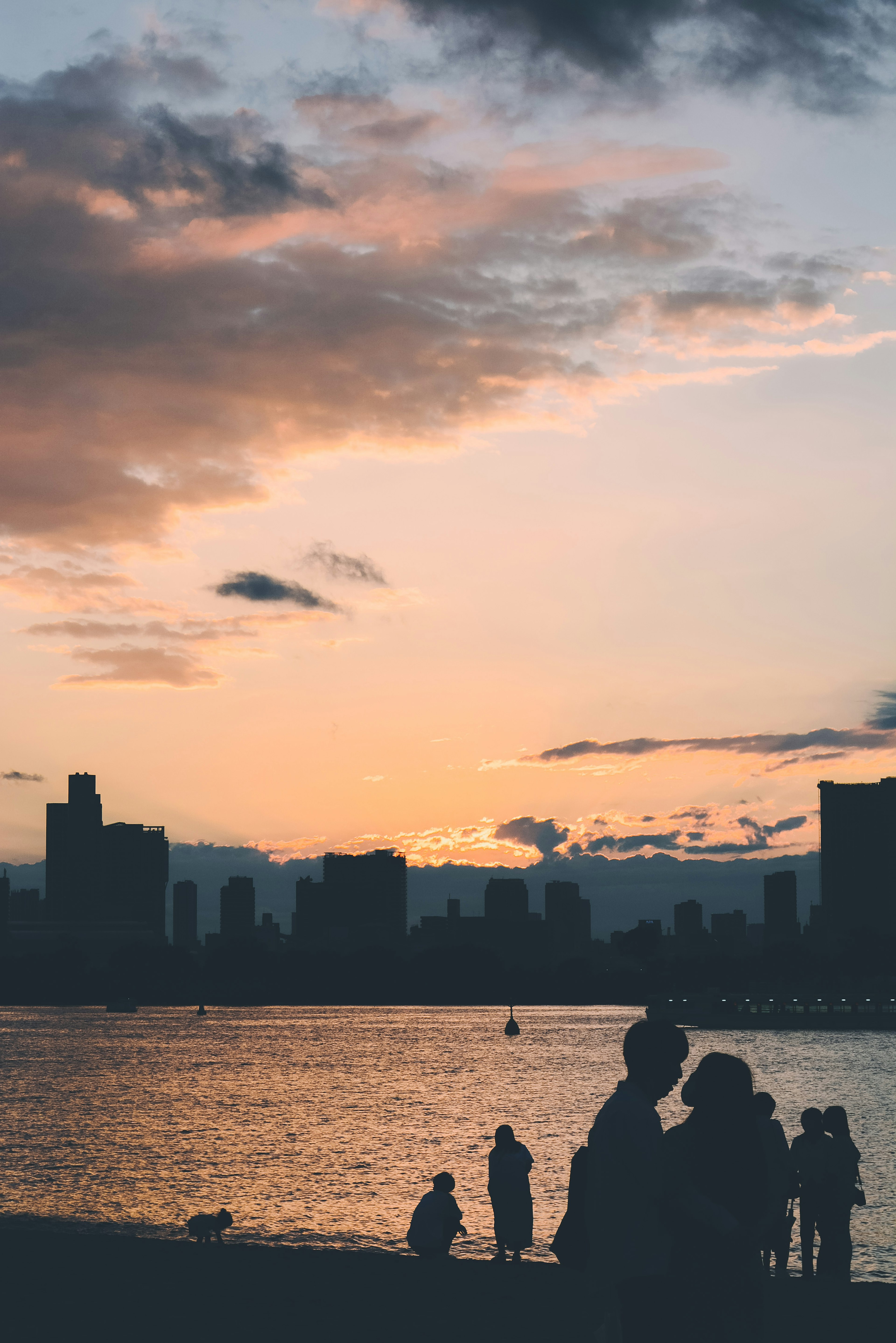 Siluetas de personas contra un atardecer con un horizonte urbano