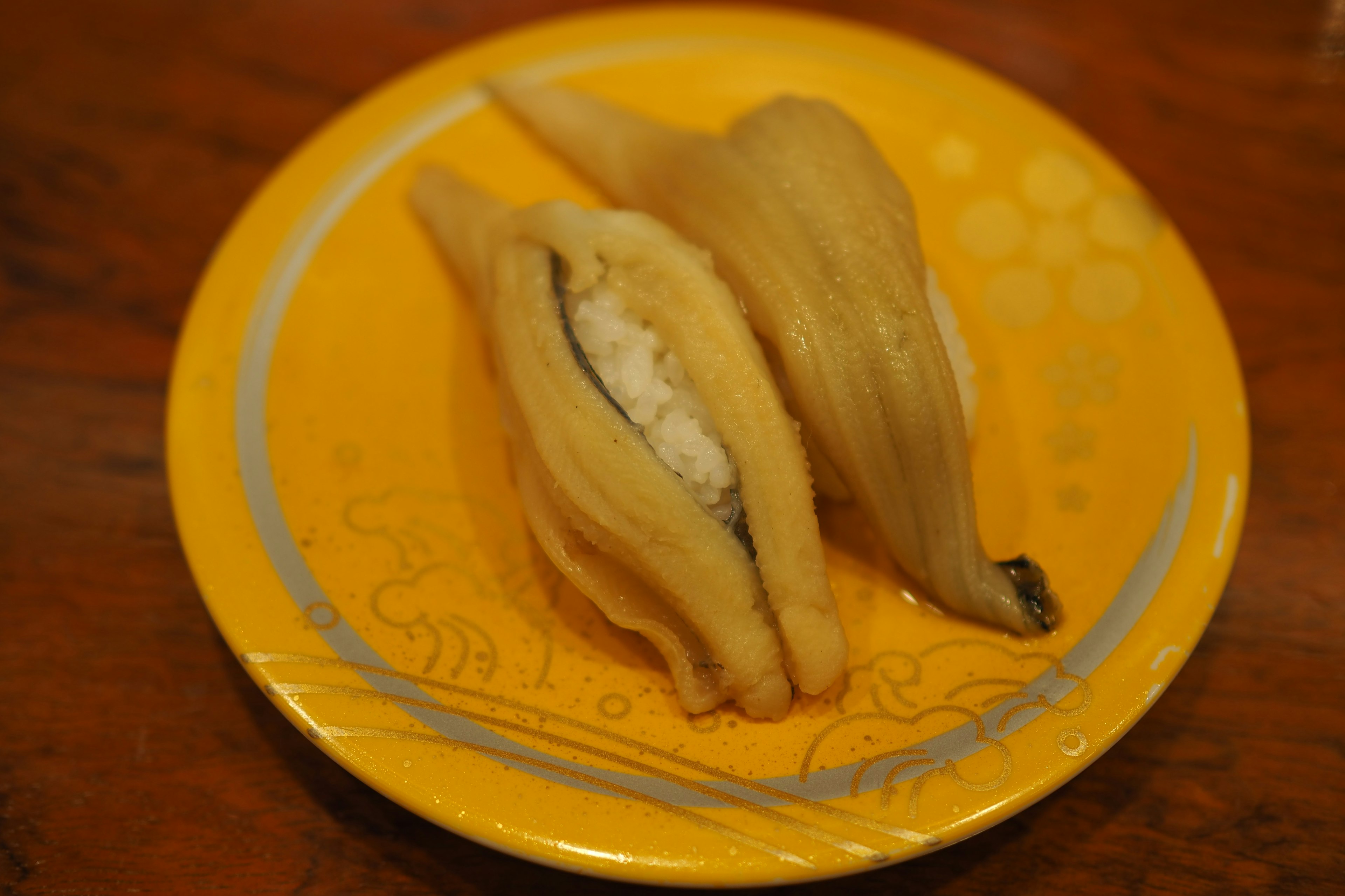 Sushi on a yellow plate featuring rice wrapped in fish