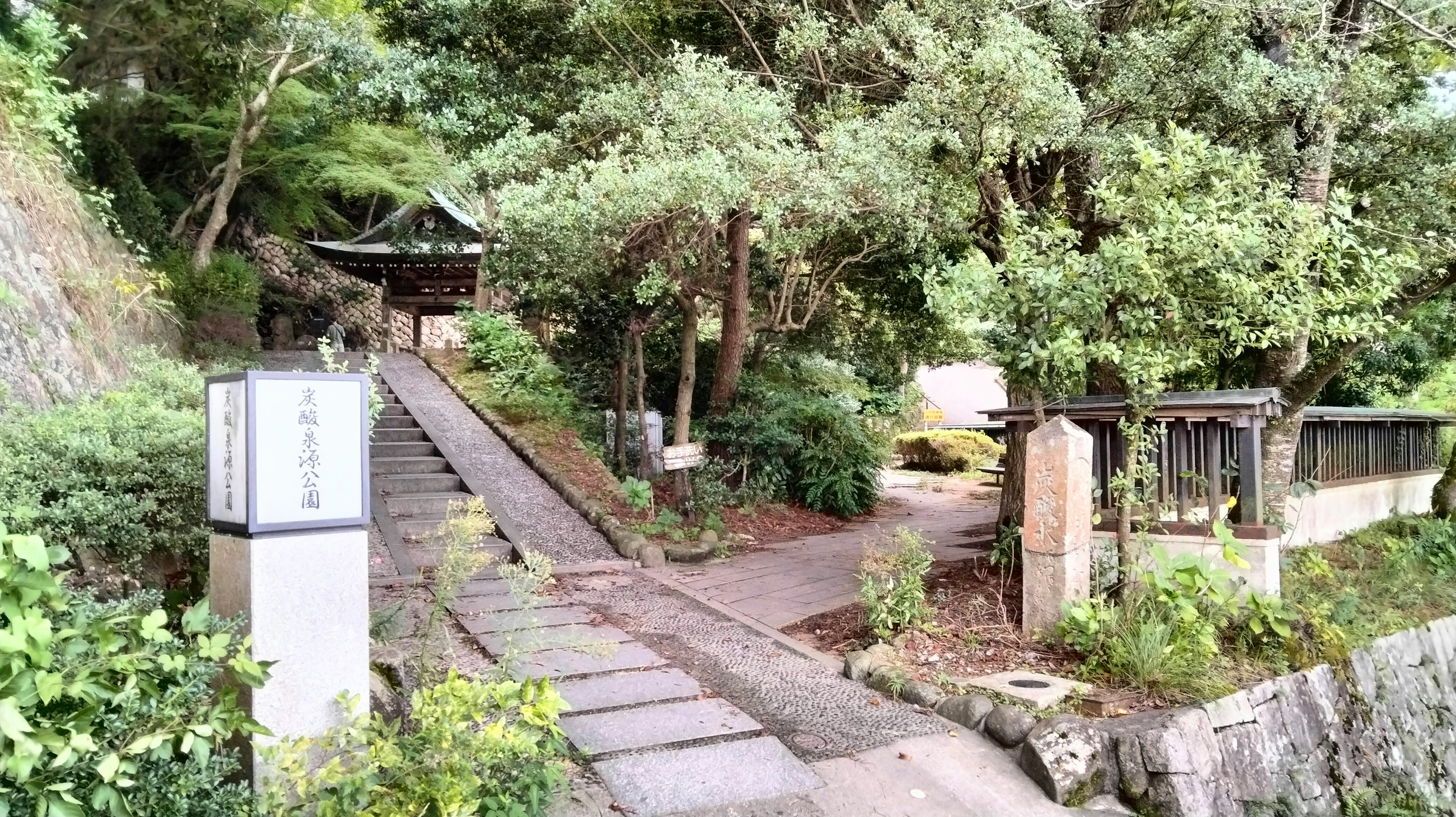 Entrée d'un temple avec un chemin en pierre entouré de verdure