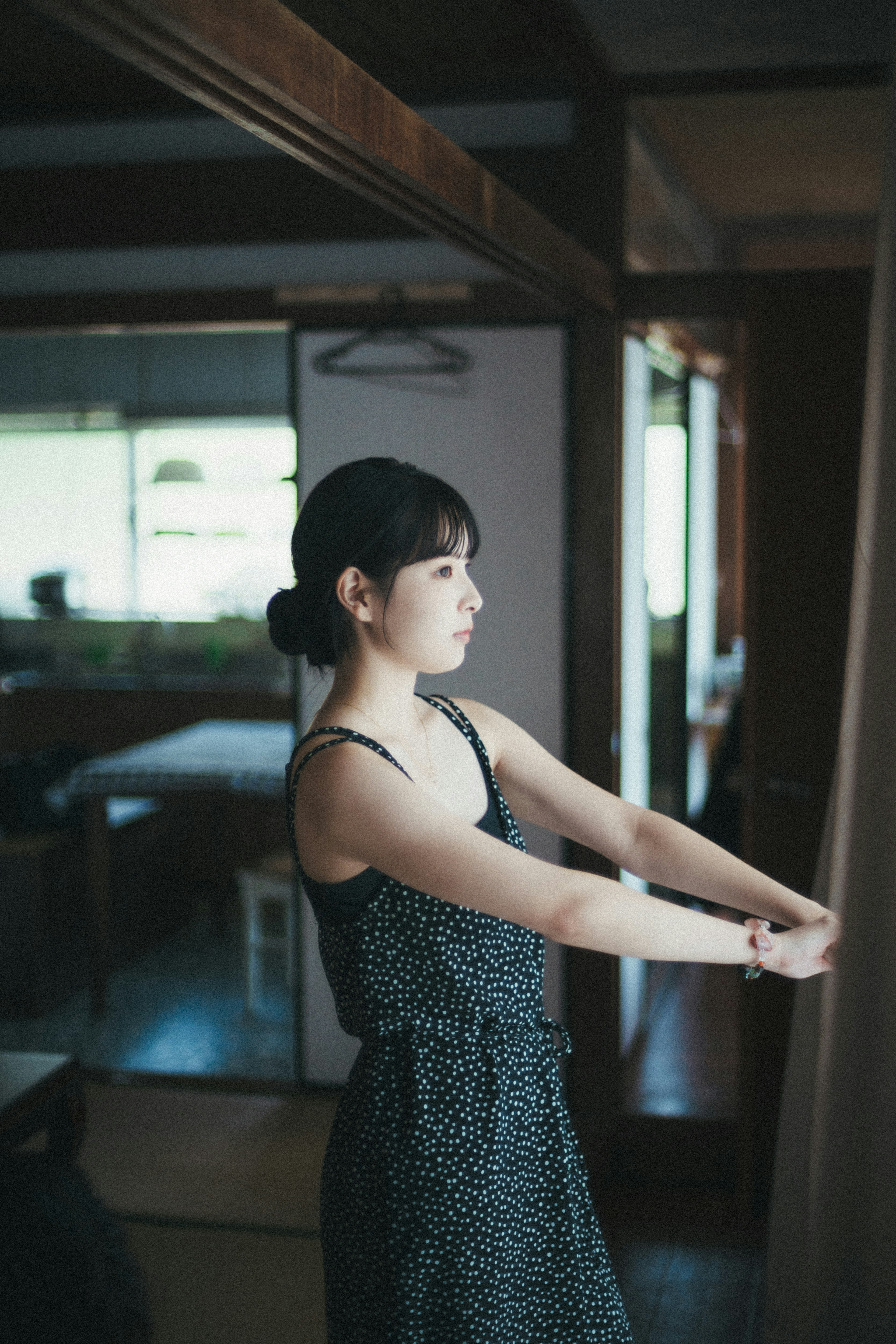 A woman pulling back curtains in a room