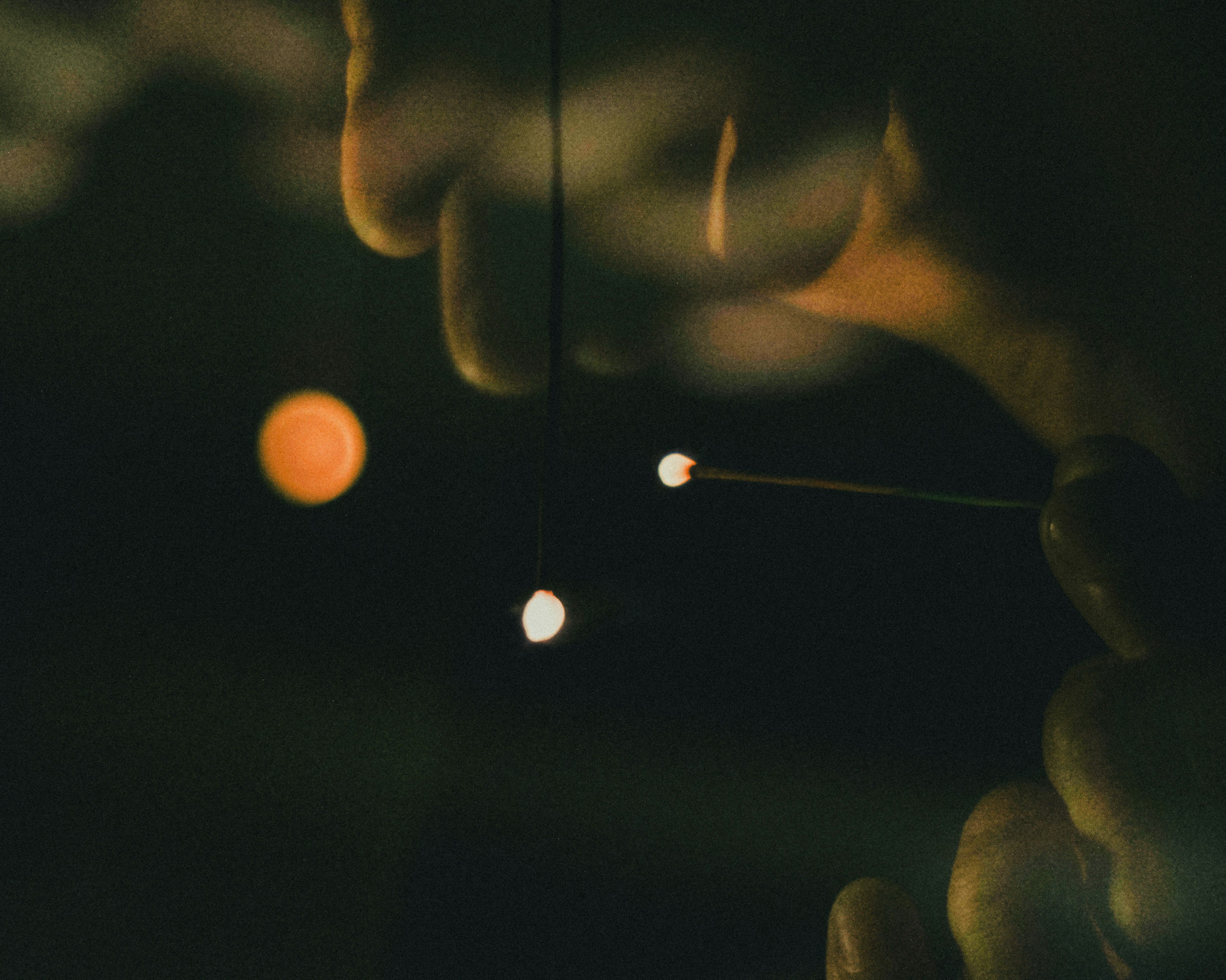 Close-up of hands holding small glowing spheres against a dark background