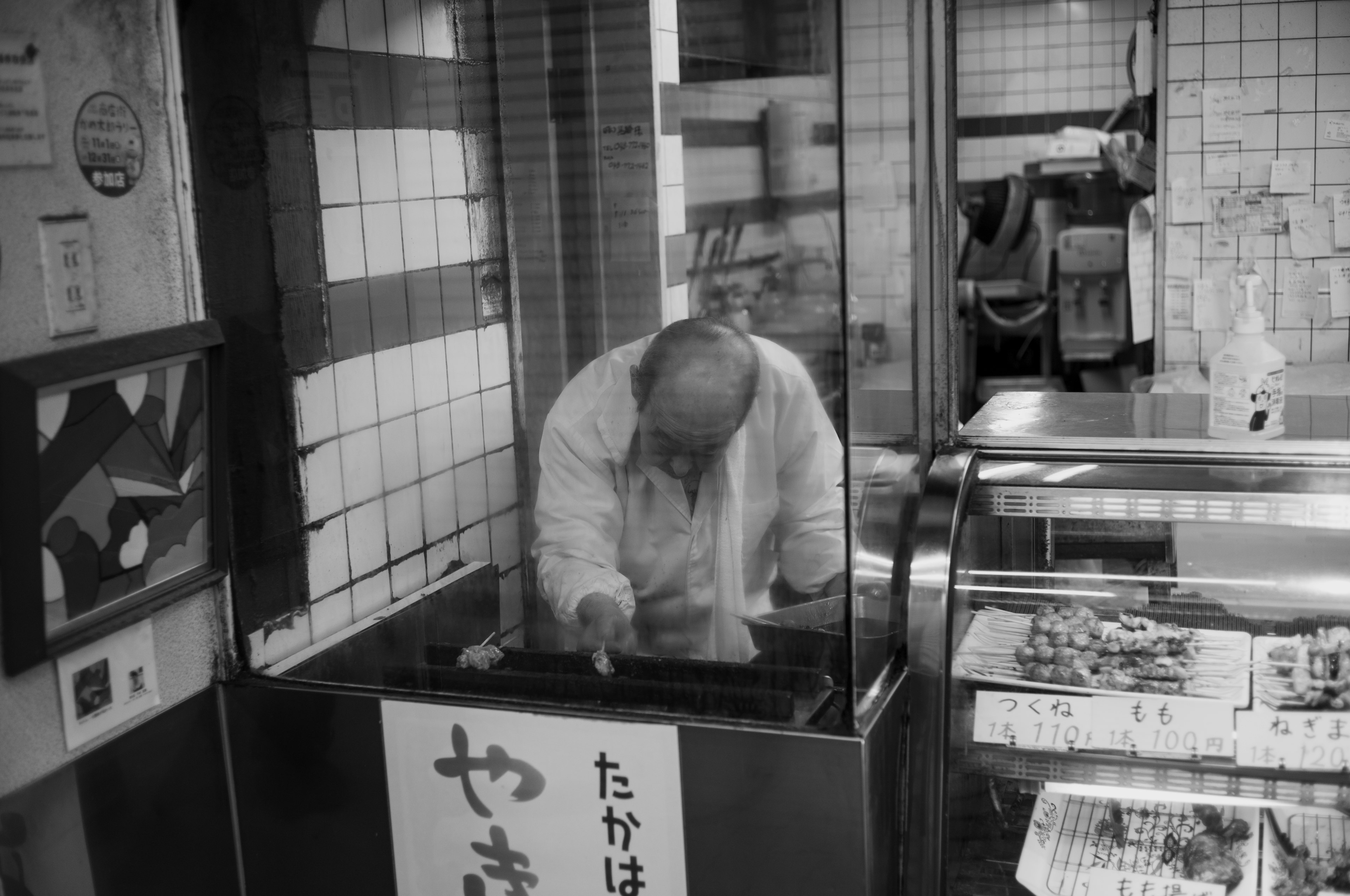 Black and white photo of a chef working in a traditional Japanese yakitori shop