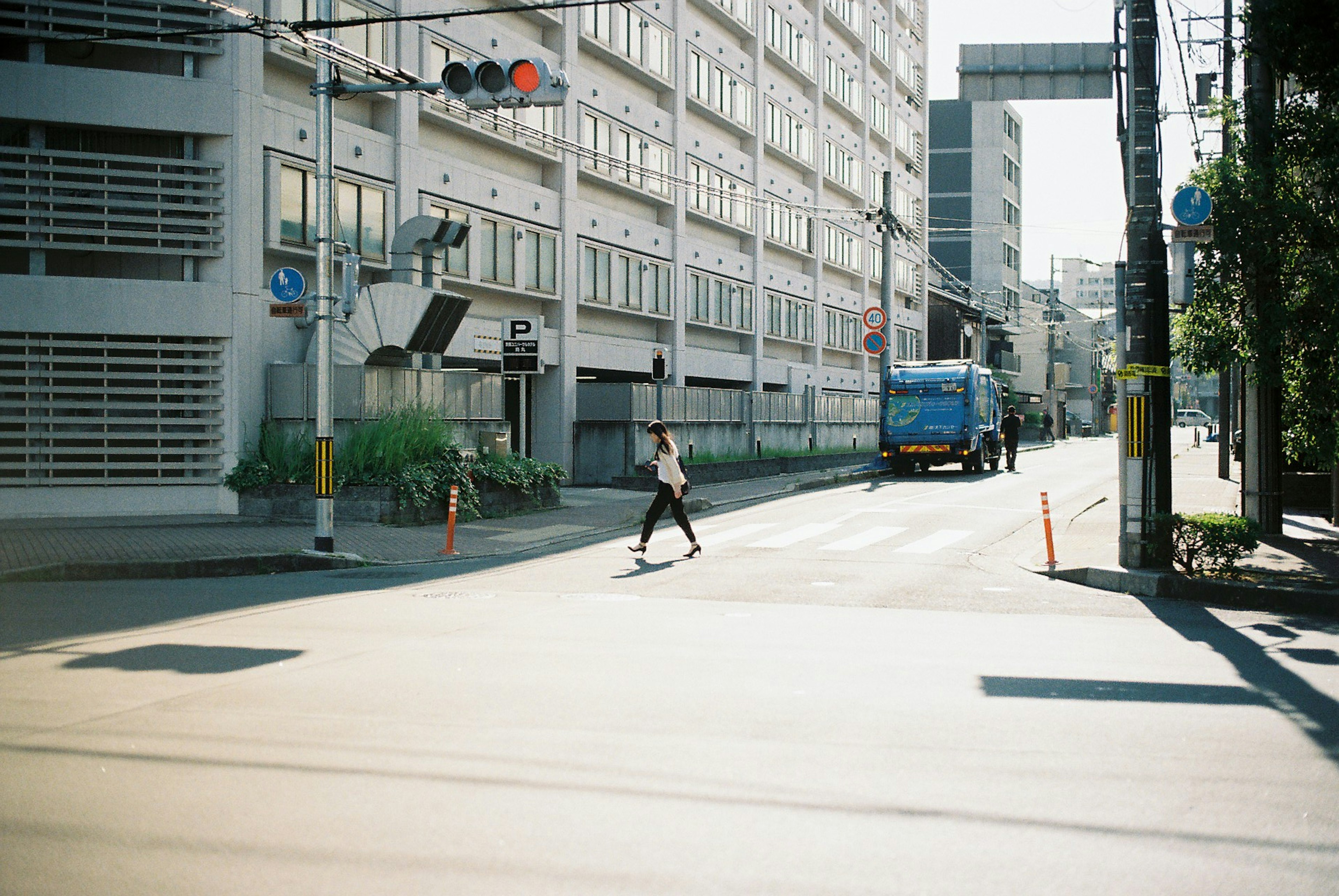 Eine Person, die die Straße unter hellem Sonnenlicht überquert, während ein Bus in einer städtischen Umgebung vorbeifährt