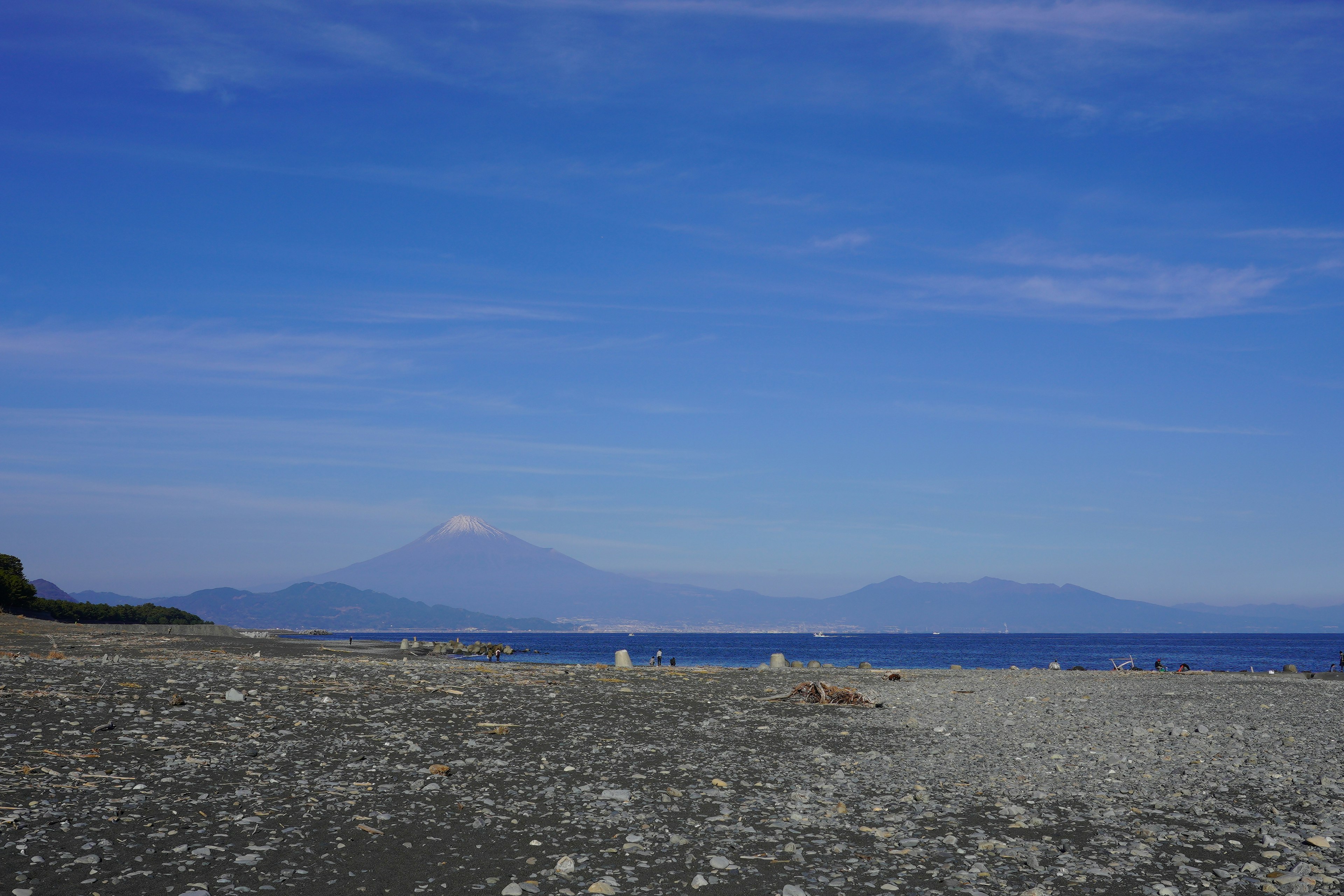 Clear blue sky over a rocky beach with distant mountains