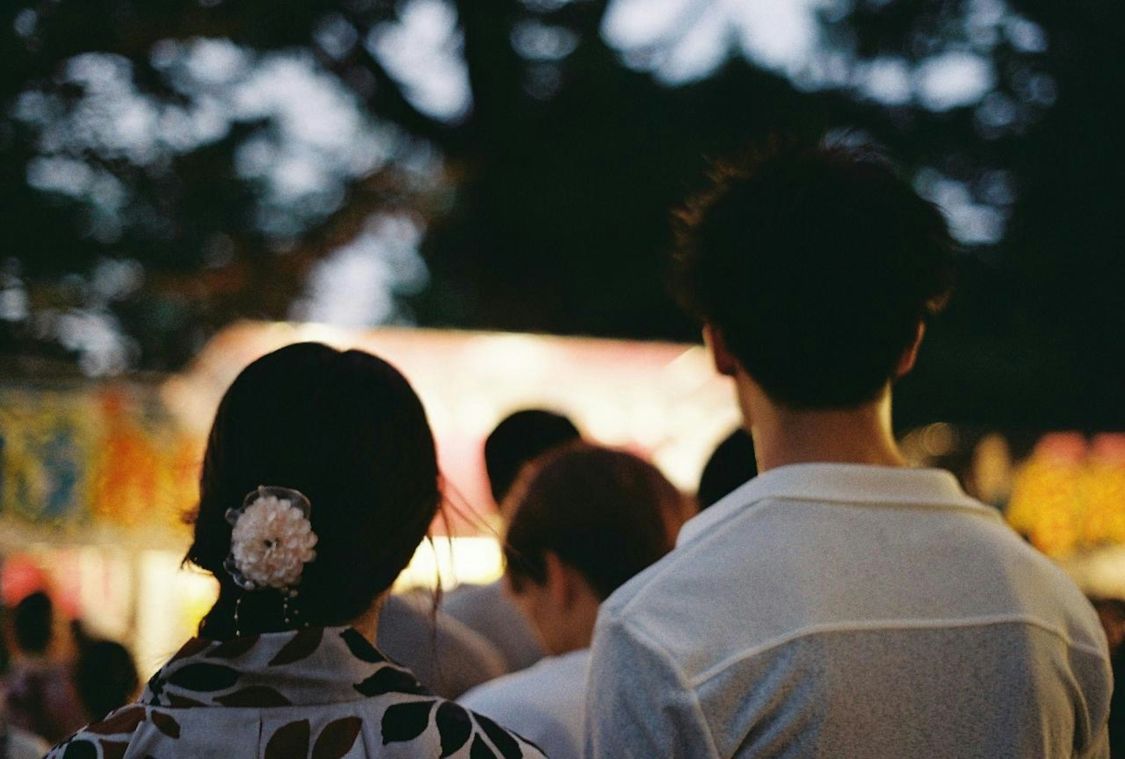 Couple enjoying a festival with their backs turned in a night setting