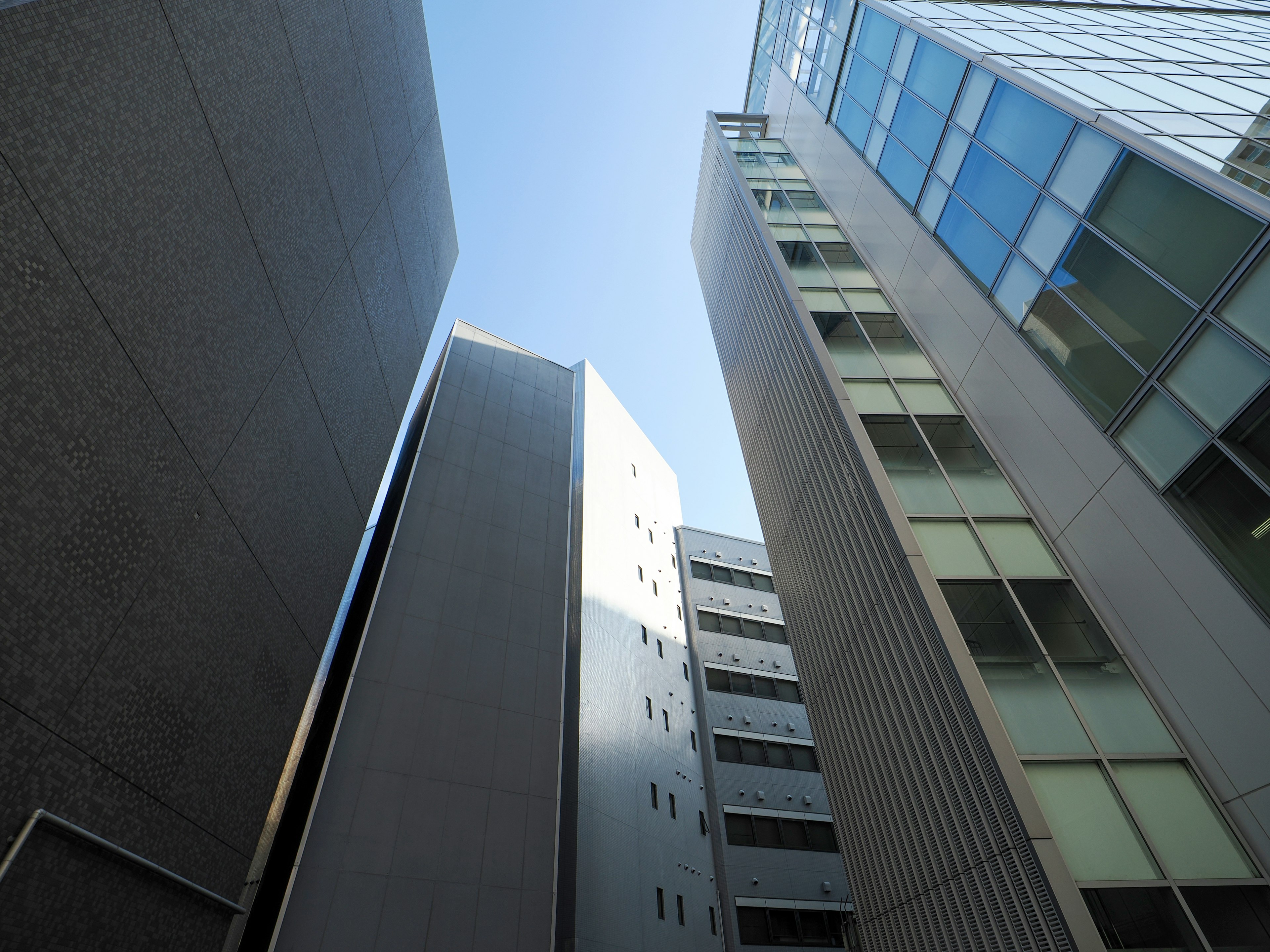 View of blue sky from between tall buildings