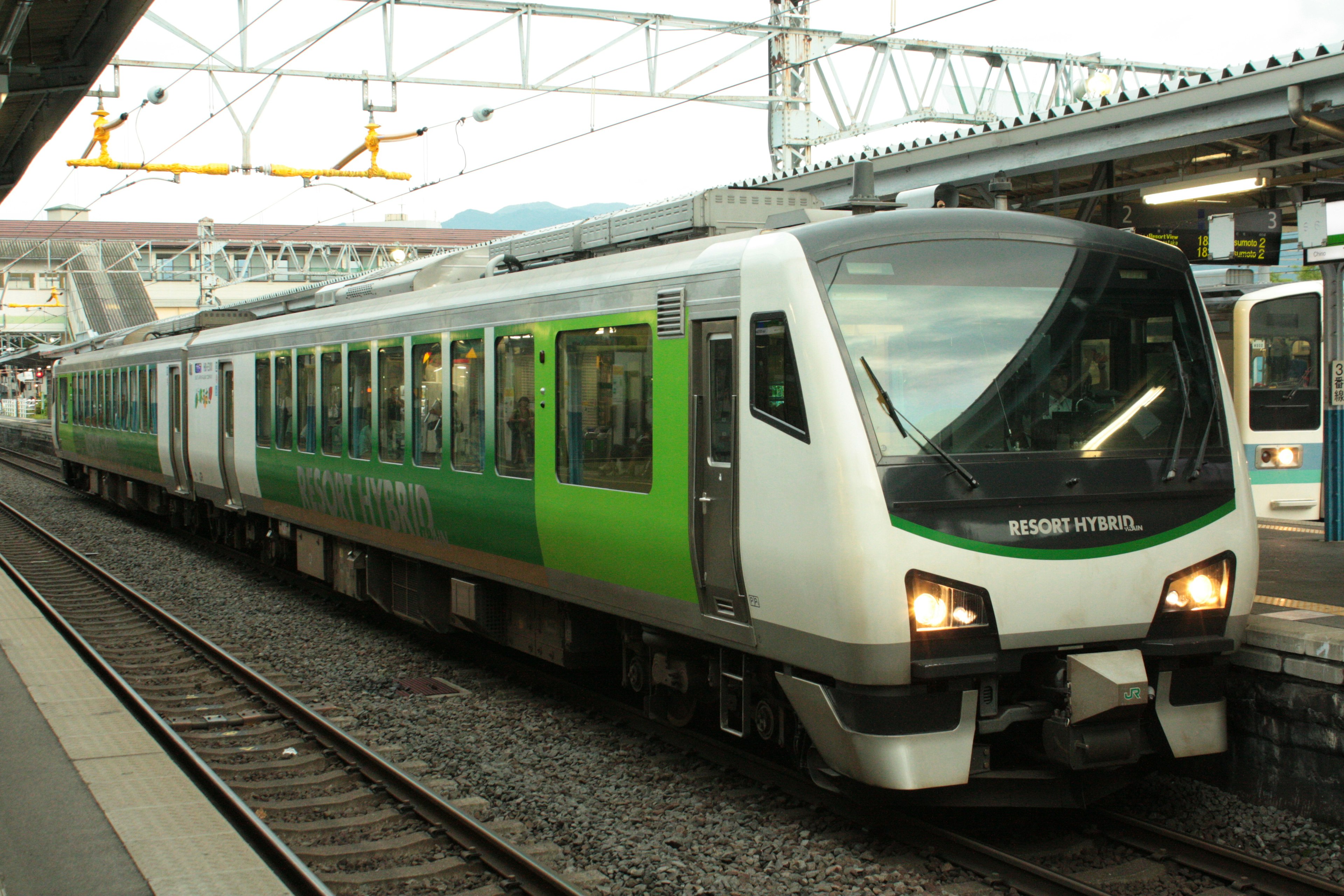 Un tren verde y blanco estacionado en una estación