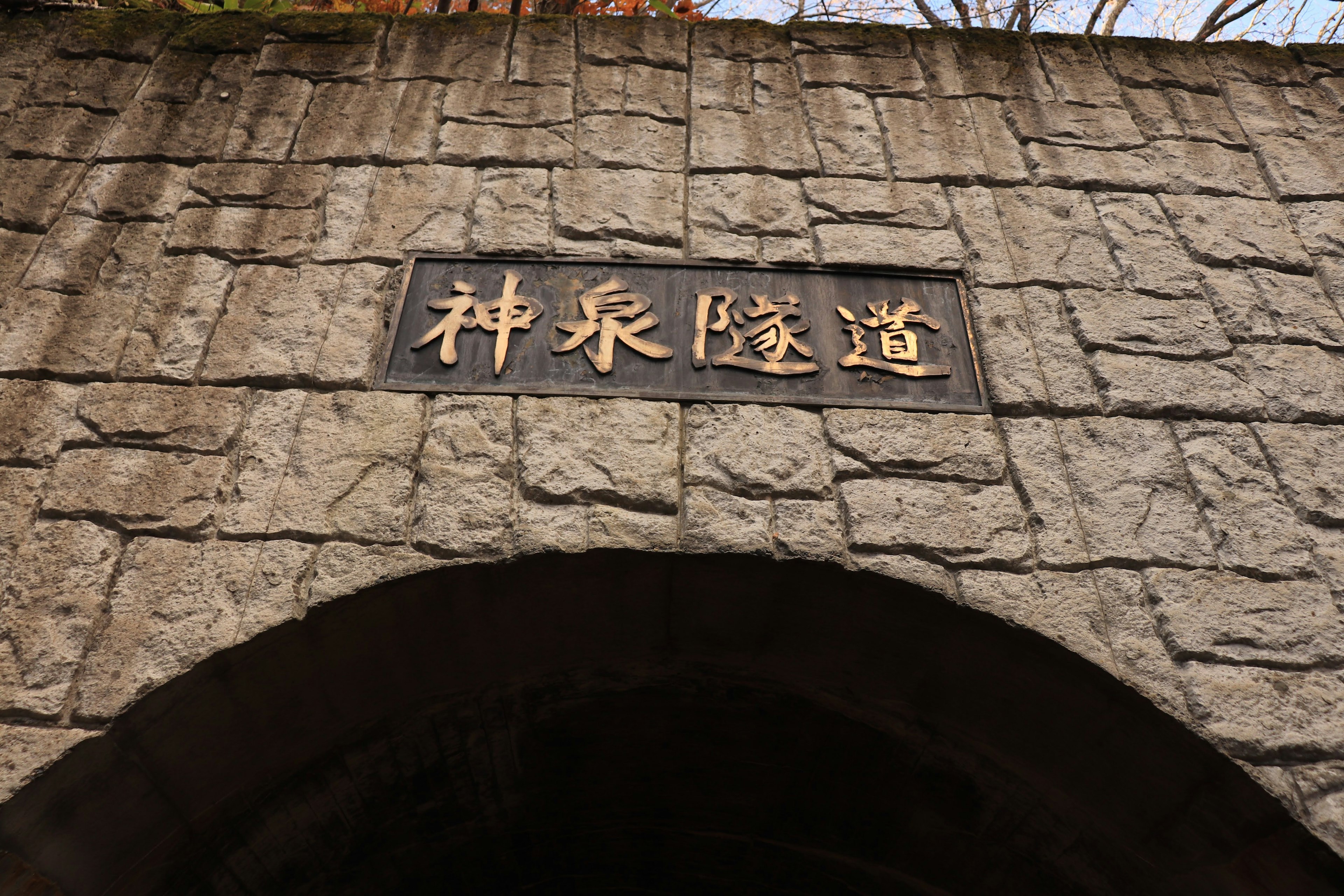 石造りのアーチの上にある金色の文字の看板 神泉隧道