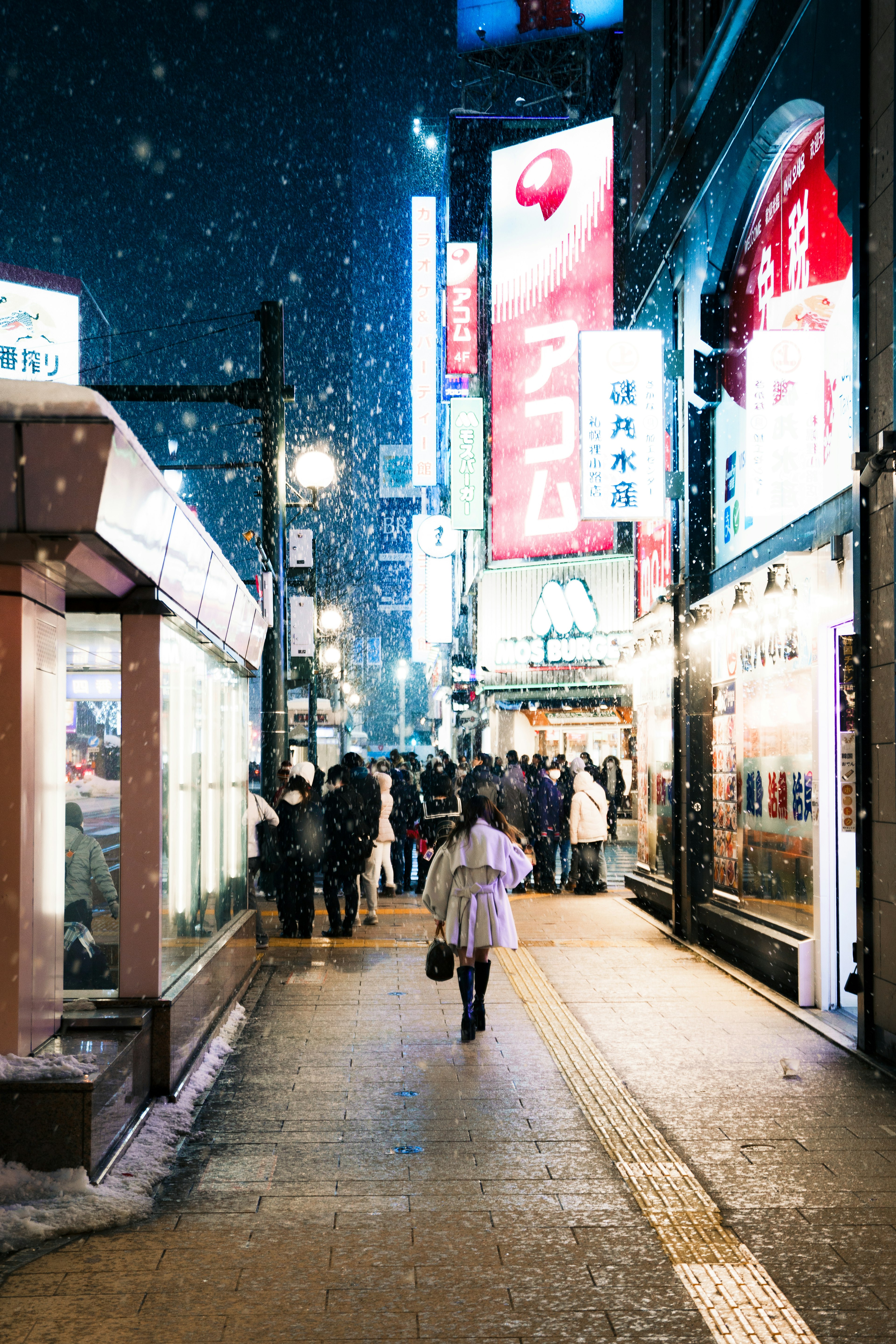 Mujer caminando en una calle nevada de noche con letreros de neón