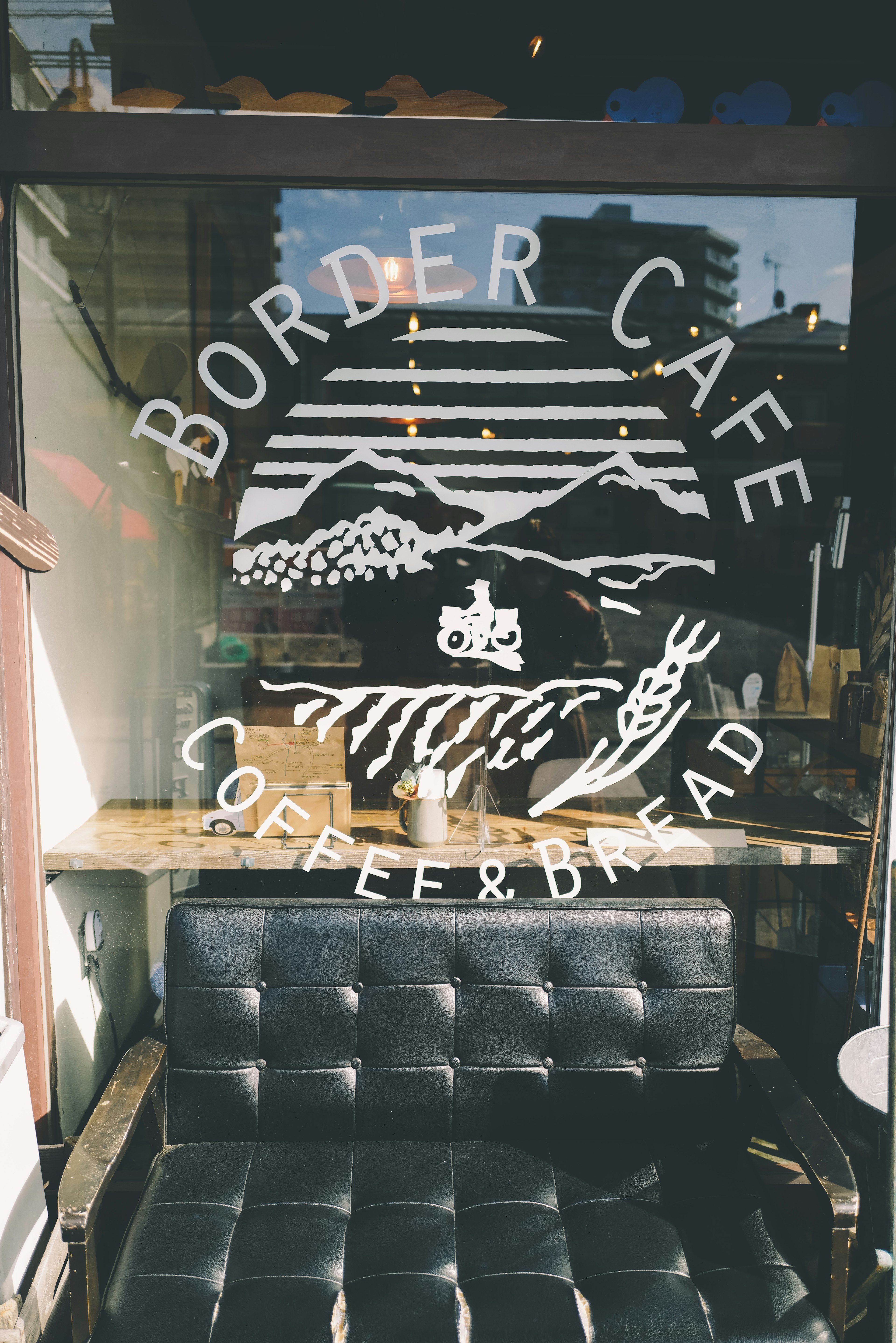 Logo du Border Café sur la fenêtre avec un canapé noir devant