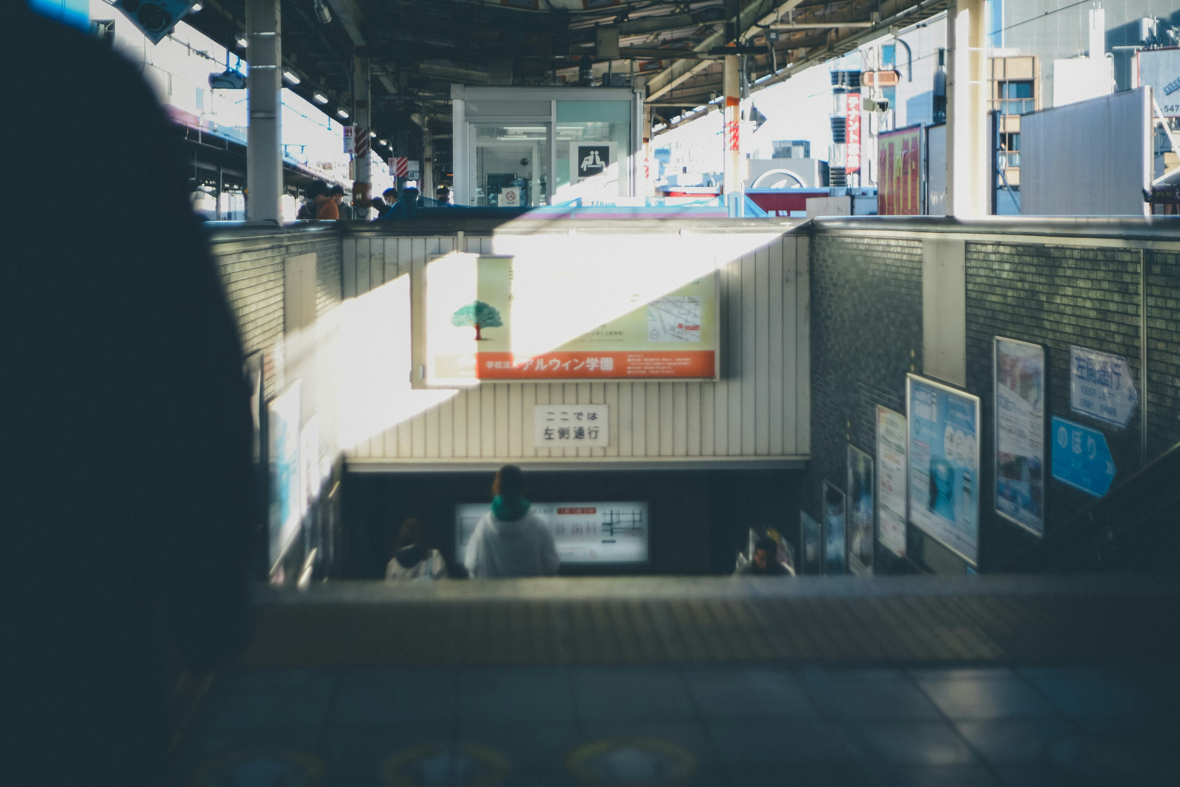 Vista de personas en la parte inferior de una escalera de estación con anuncios