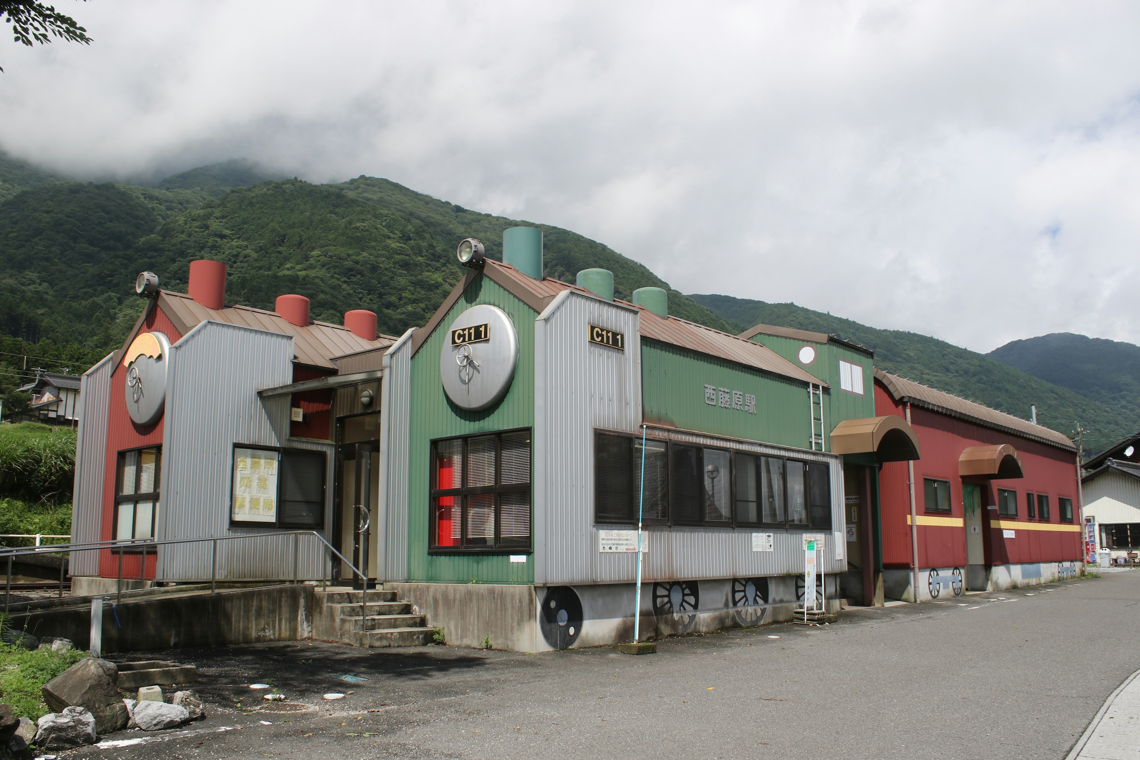 Edificio único con exterior verde y rojo ubicado cerca de montañas