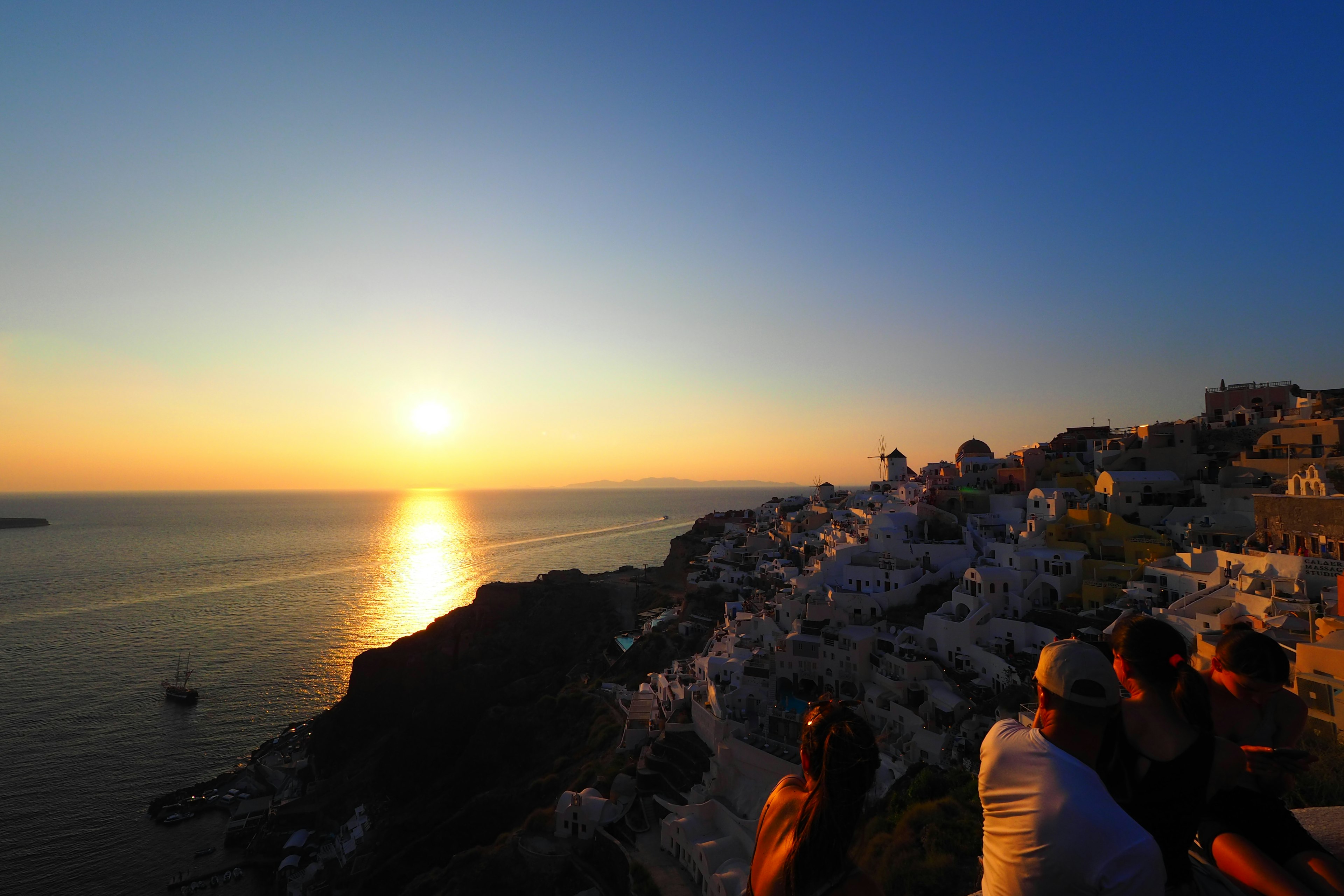 サントリーニの美しい夕日と海の景色を背景にした観光客