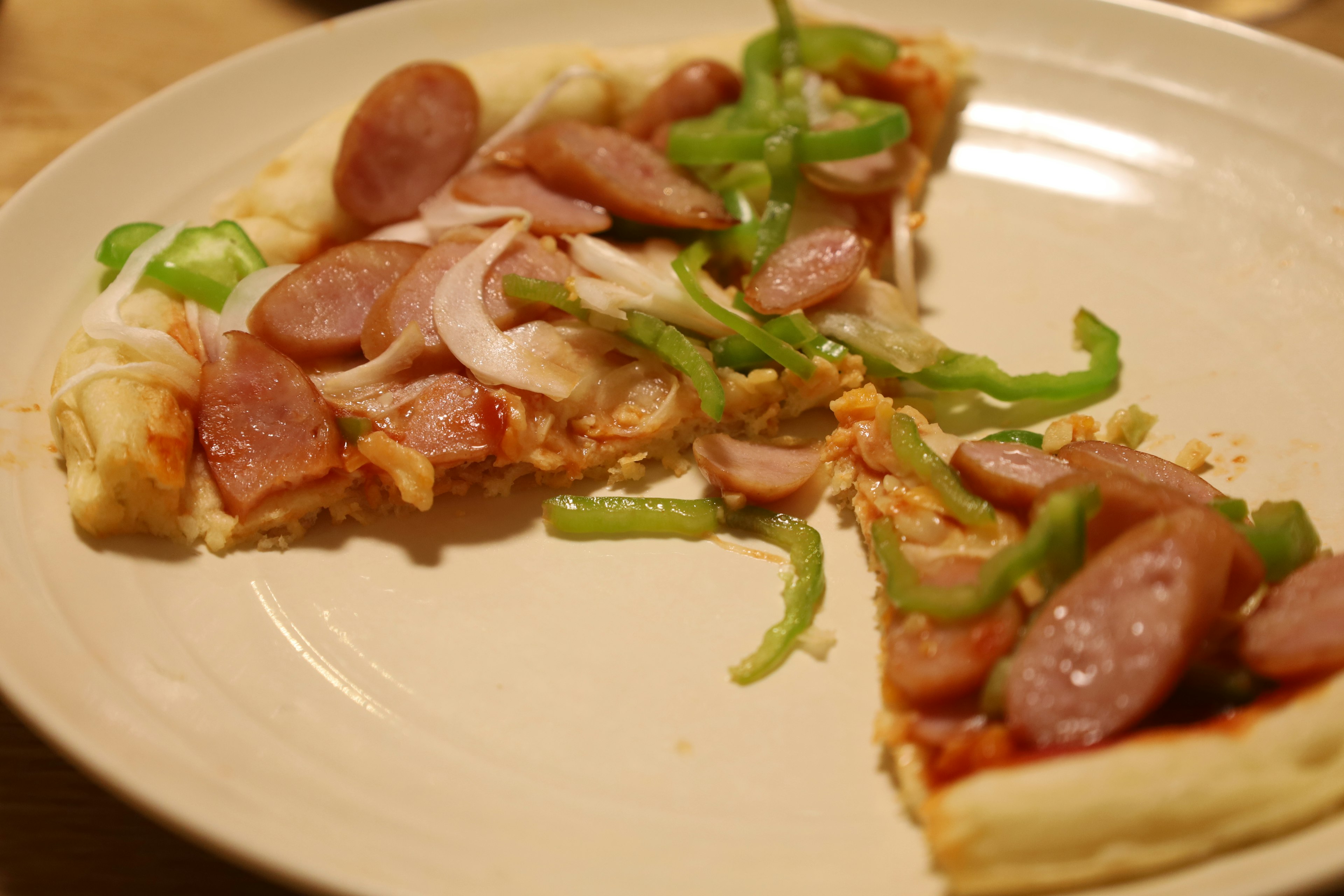 Rebanada de pizza cubierta con salchichas y pimientos verdes