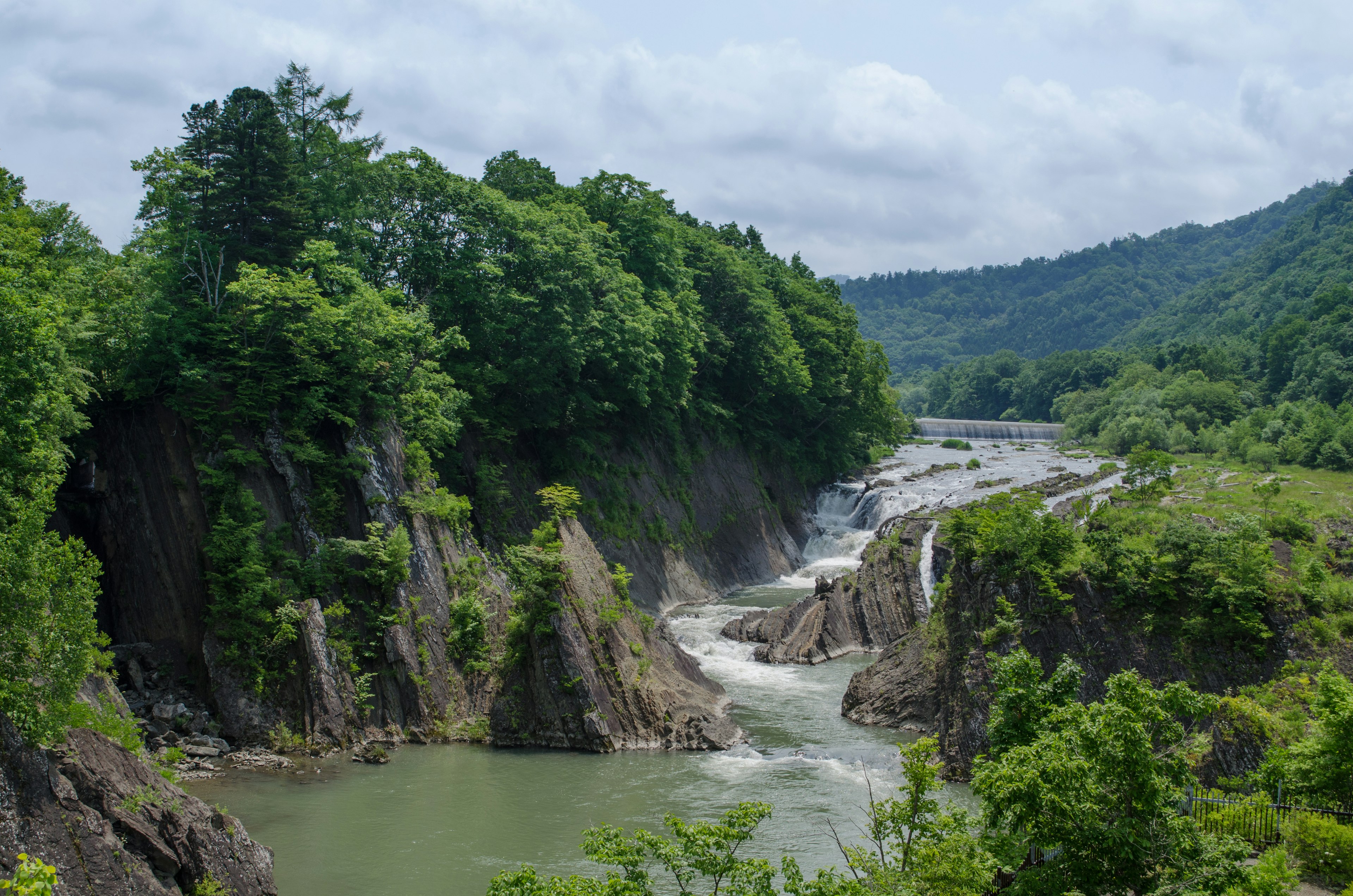 Vista panoramica di un fiume che scorre tra montagne verdi e rocce