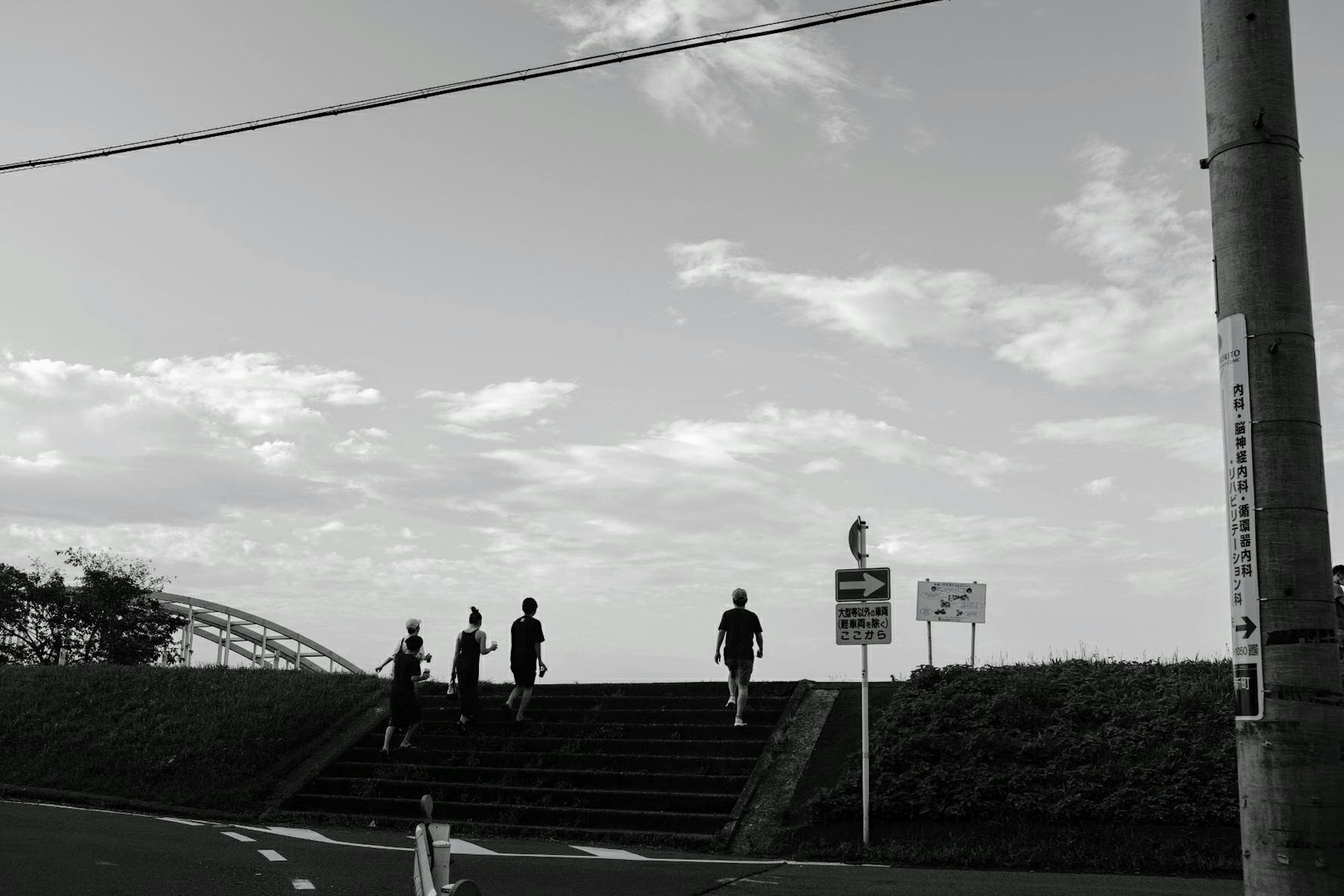 階段を上る人々と白黒の空が広がる風景