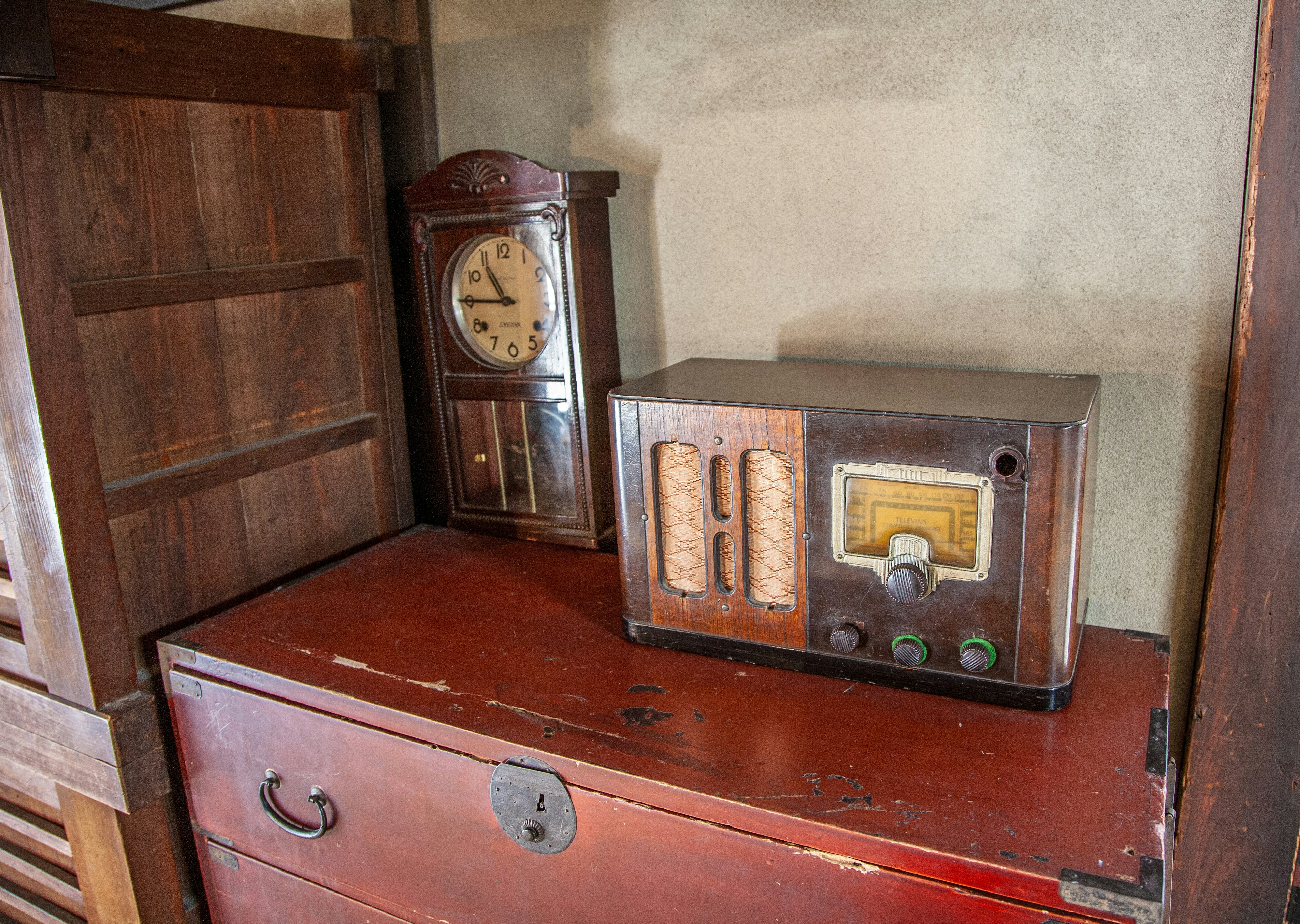 An antique radio and clock placed on a wooden shelf