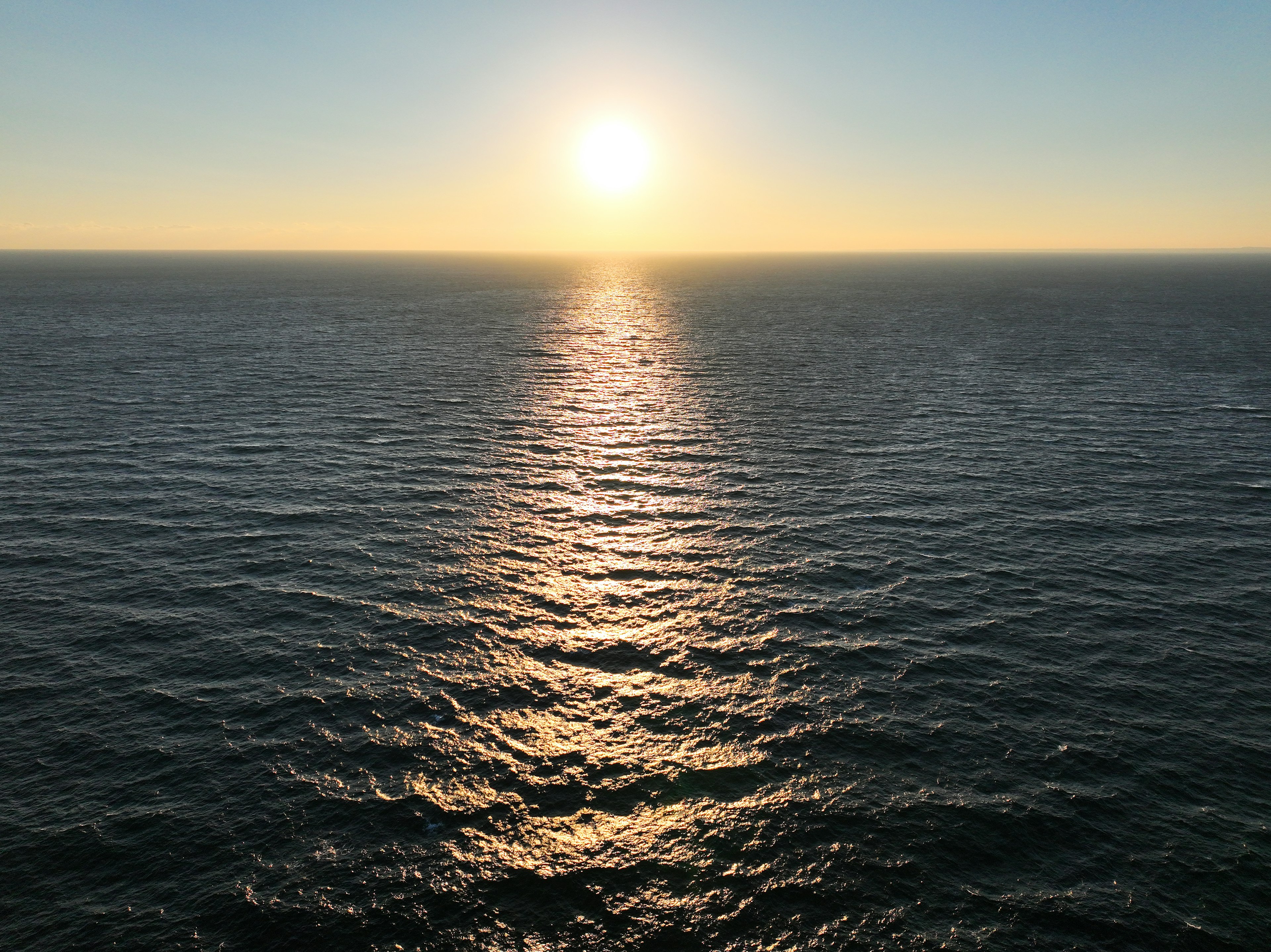 太陽が海に沈む風景、波の反射、穏やかな水面