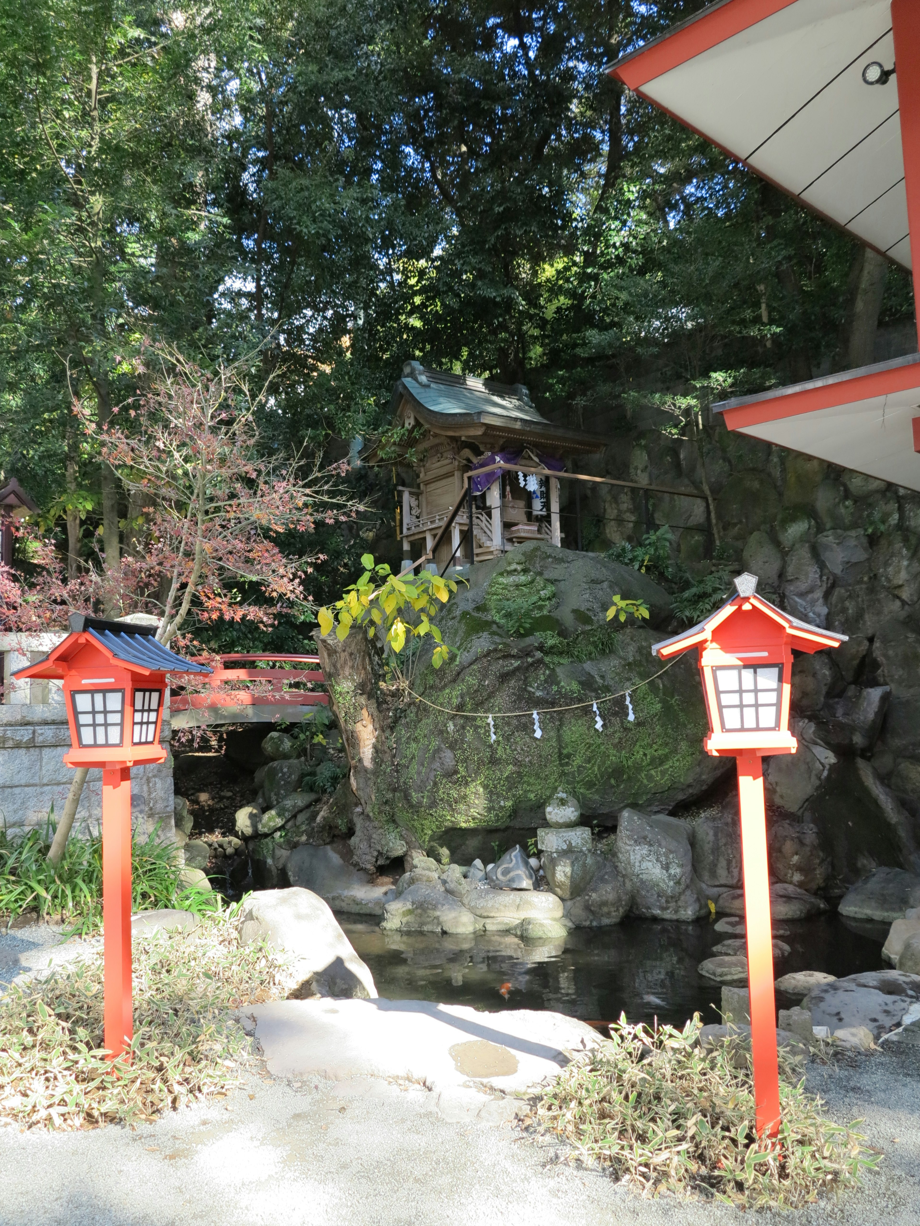 赤い灯篭が立つ日本庭園の風景小さな橋と神社が見える