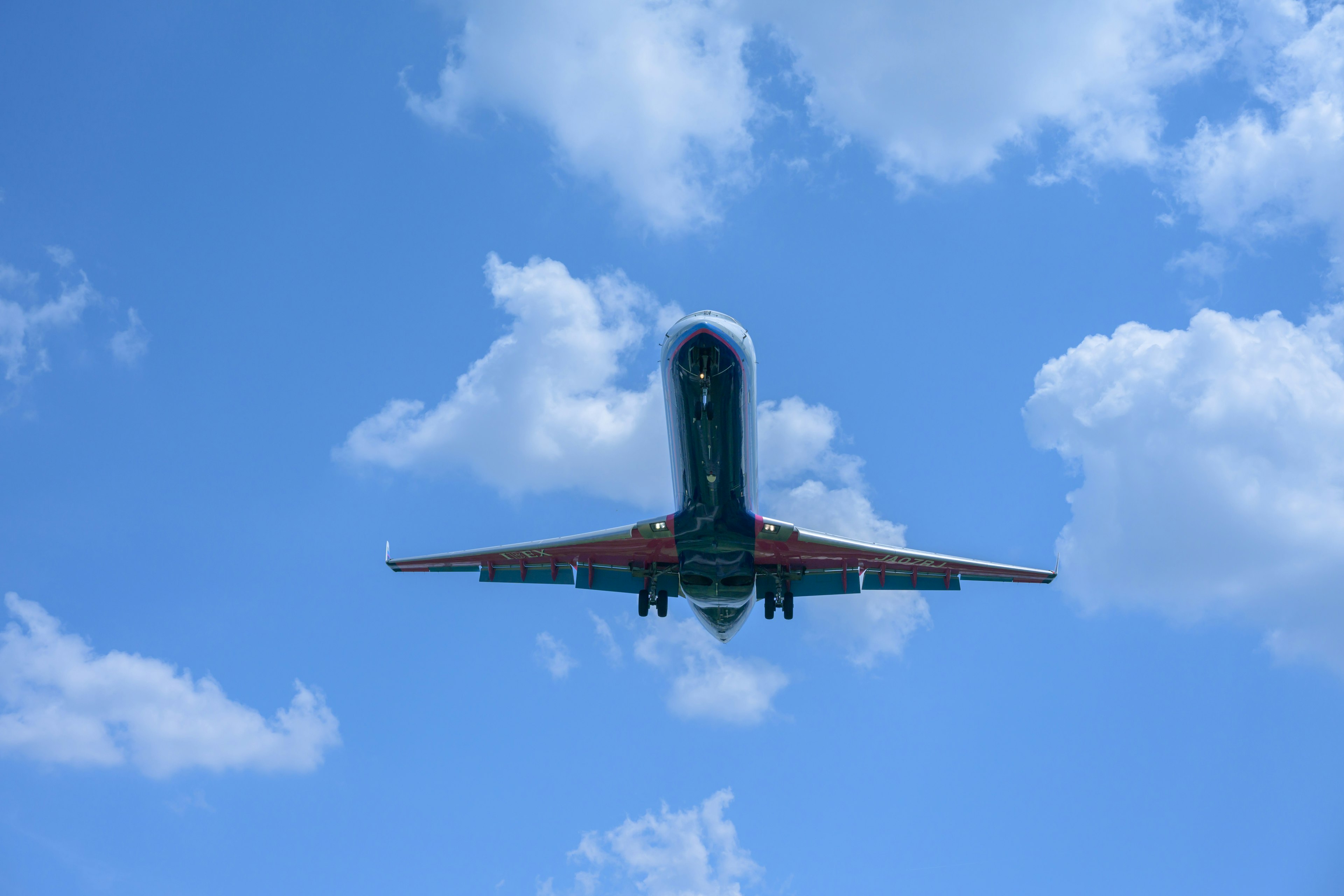 Flugzeug fliegt gegen einen blauen Himmel mit Wolken von unten