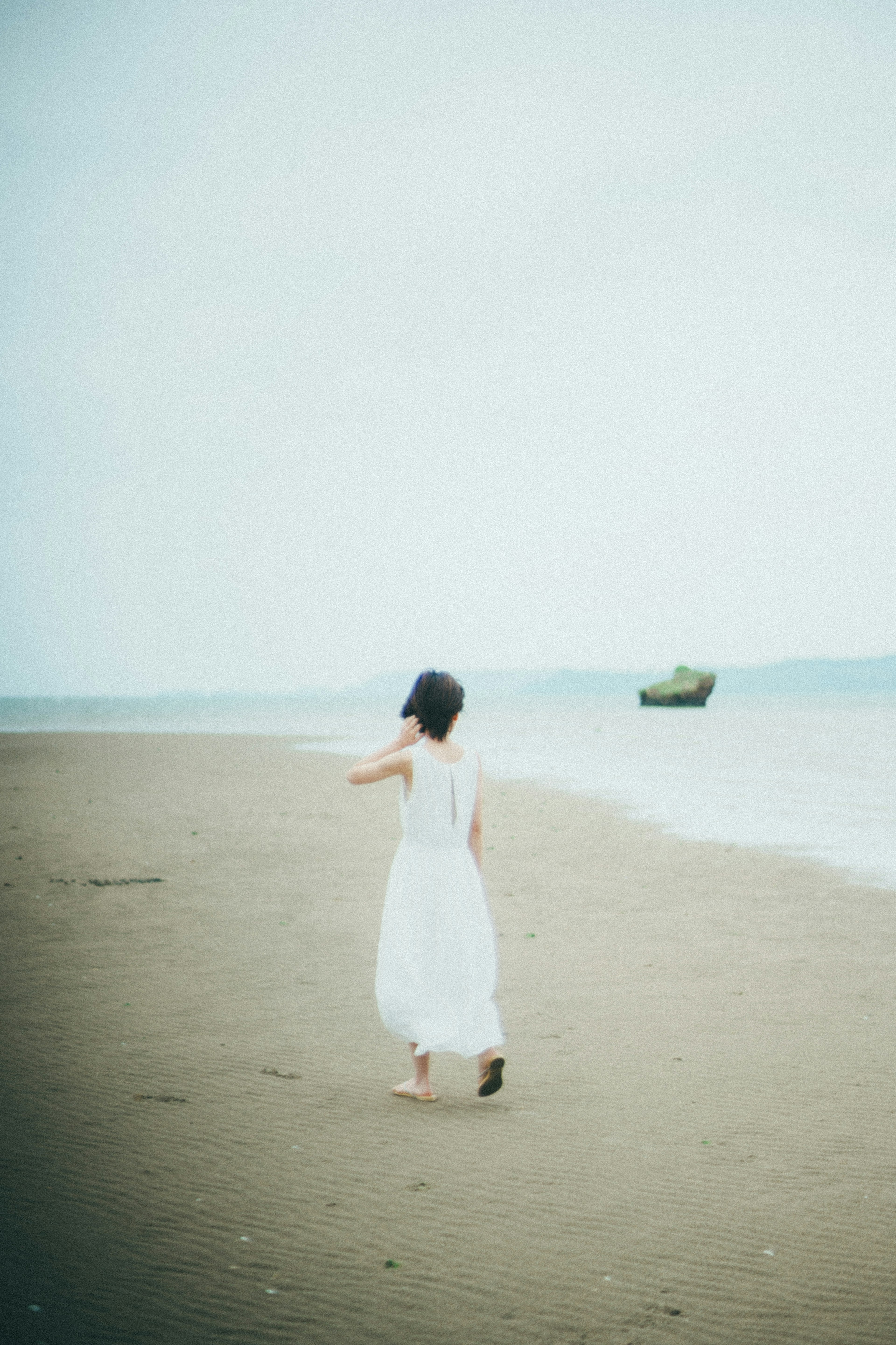 A woman in a white dress walking on a serene beach