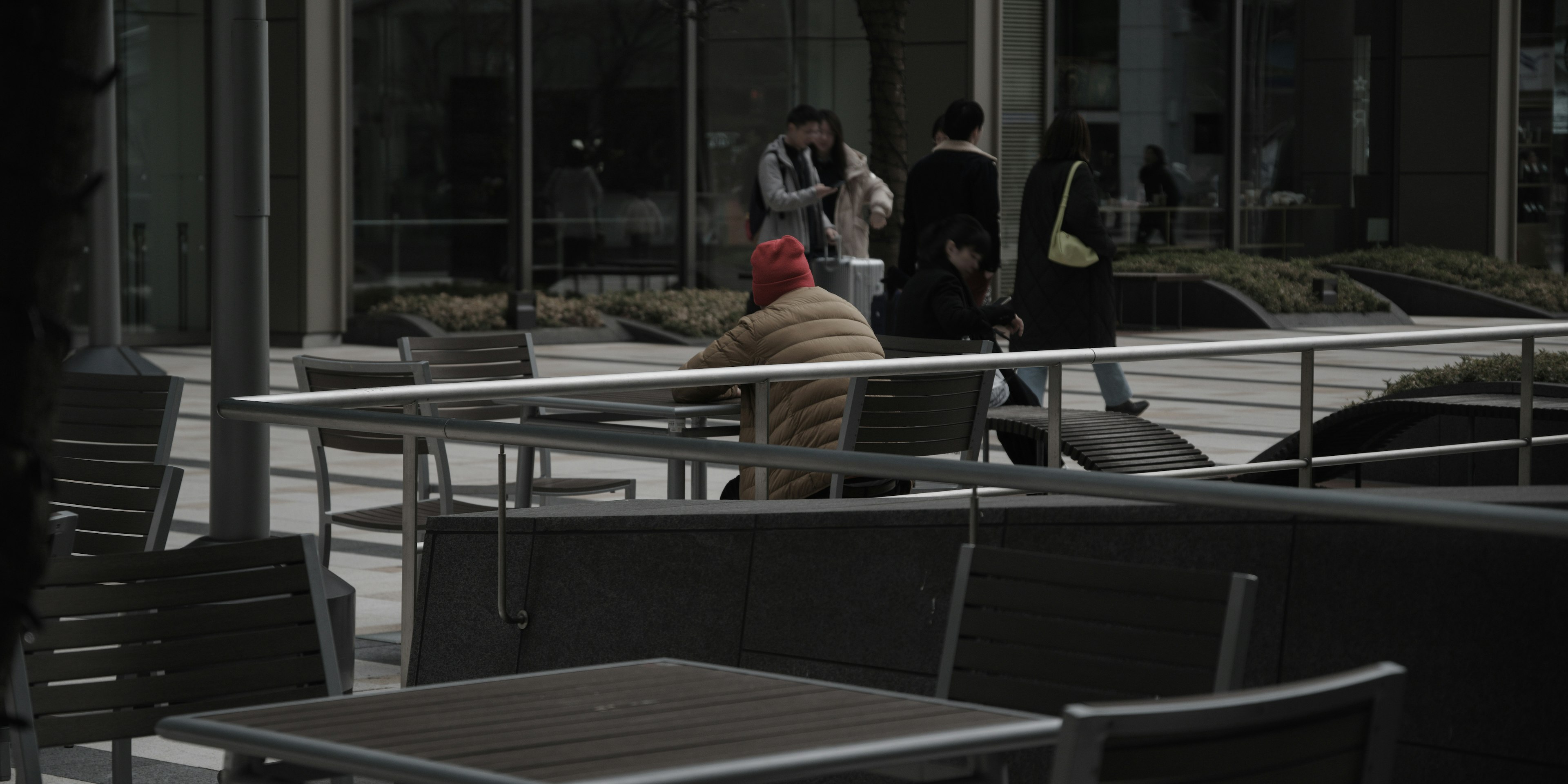 Una persona seduta su una terrazza di caffè con altre persone nelle vicinanze