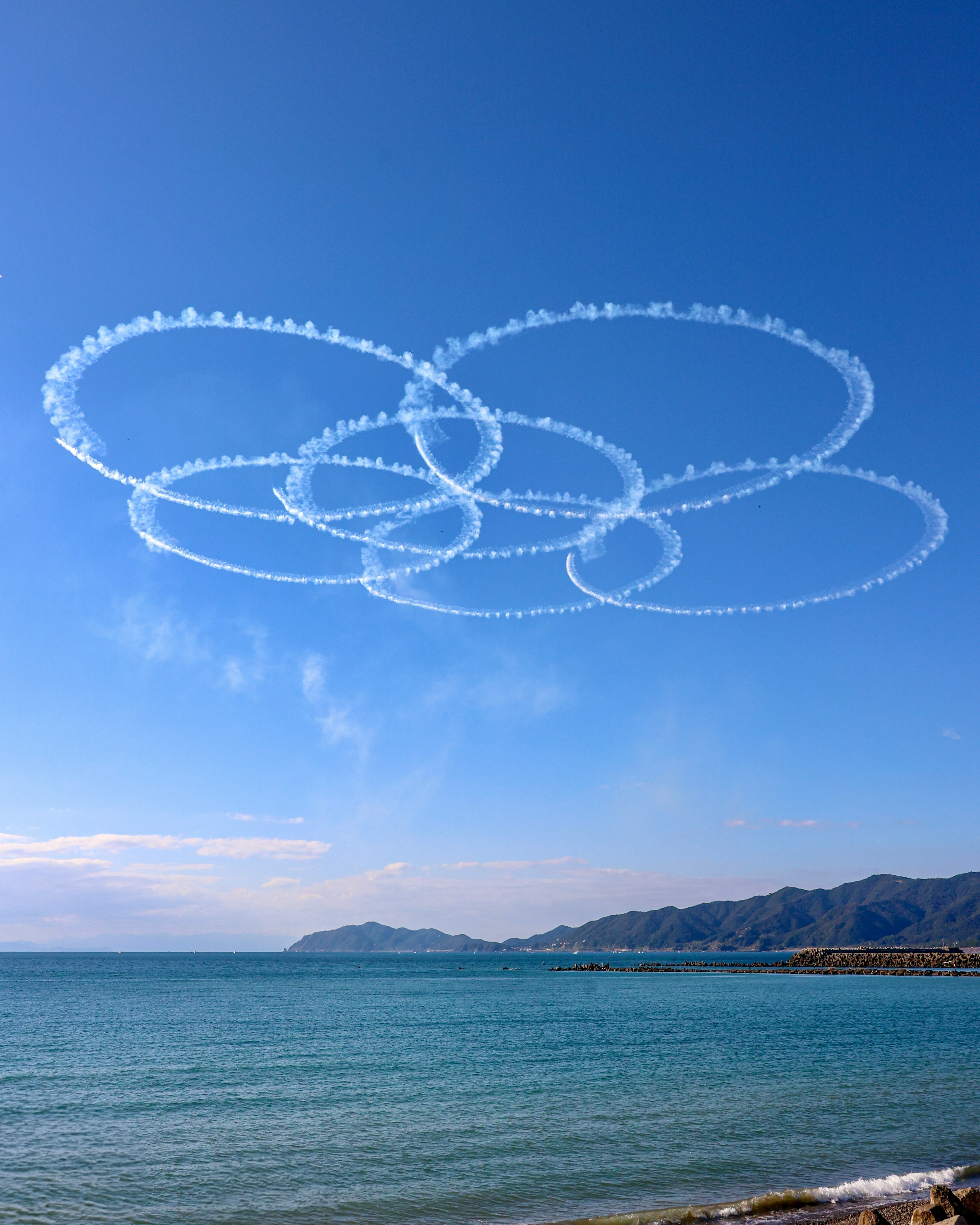 Anelli di fumo bianco nel cielo blu sopra l'oceano calmo