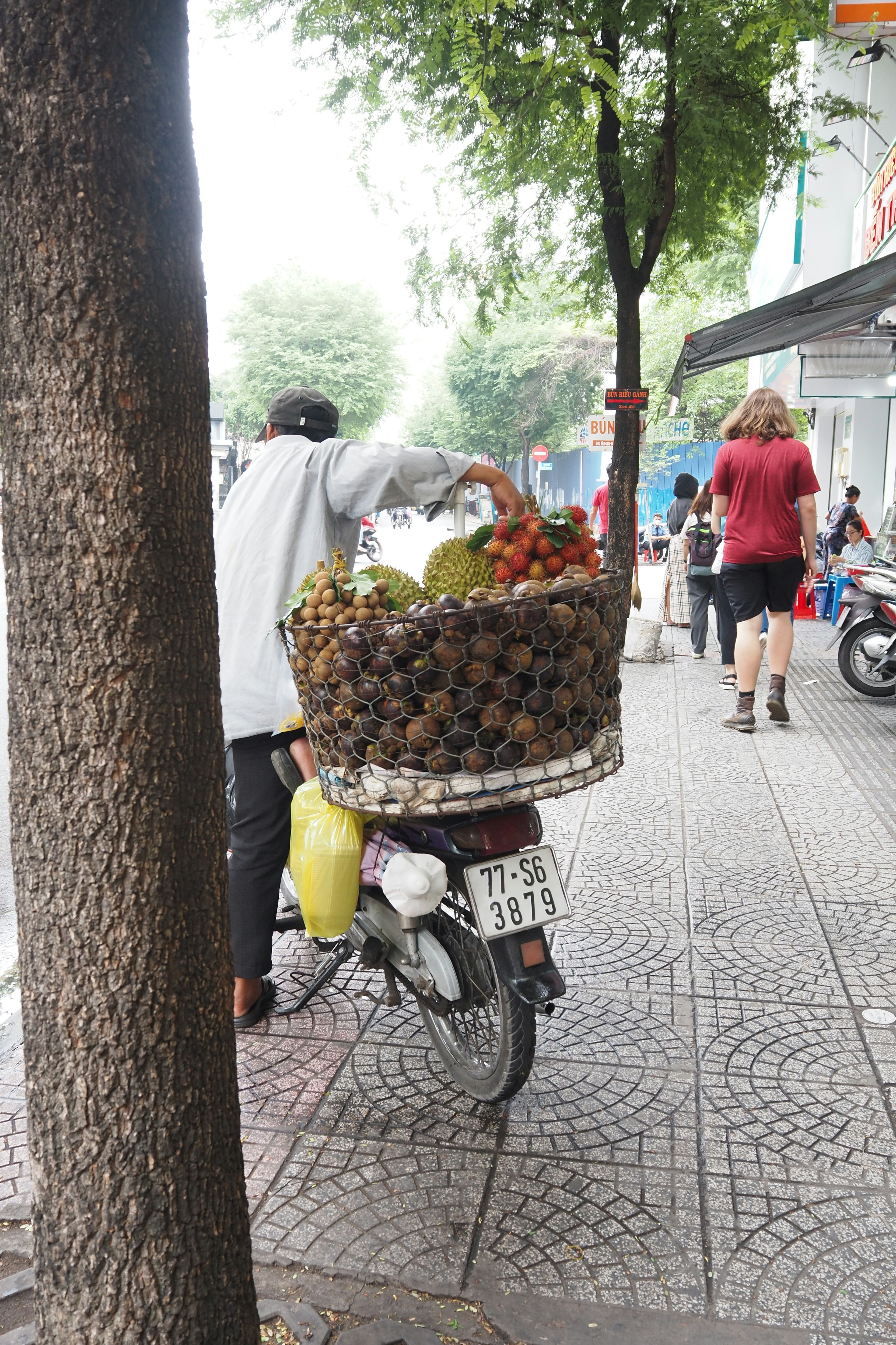 Un vendedor de frutas en bicicleta llevando una gran canasta de frutas en un entorno urbano