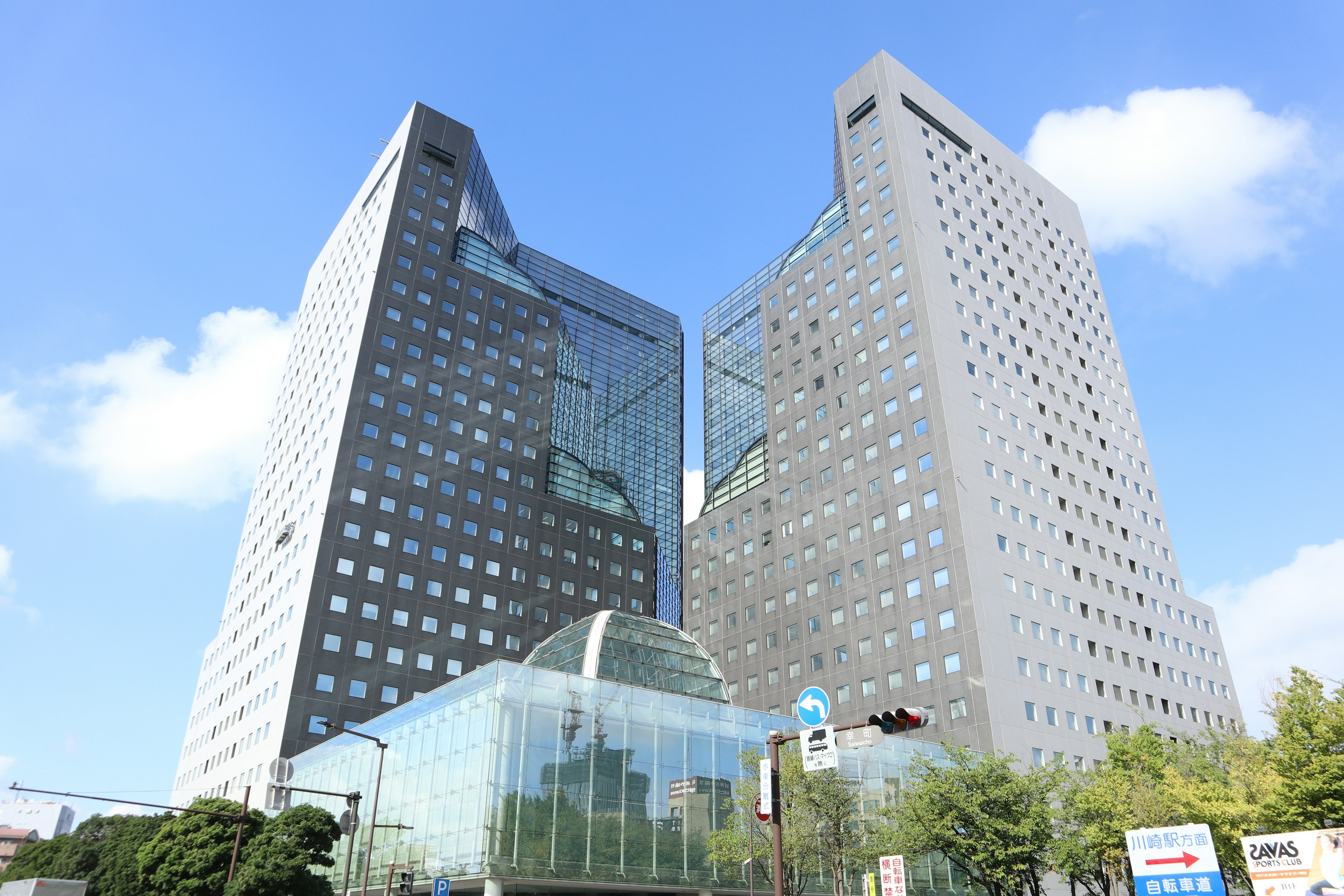 Two modern skyscrapers with glass entrance and blue sky