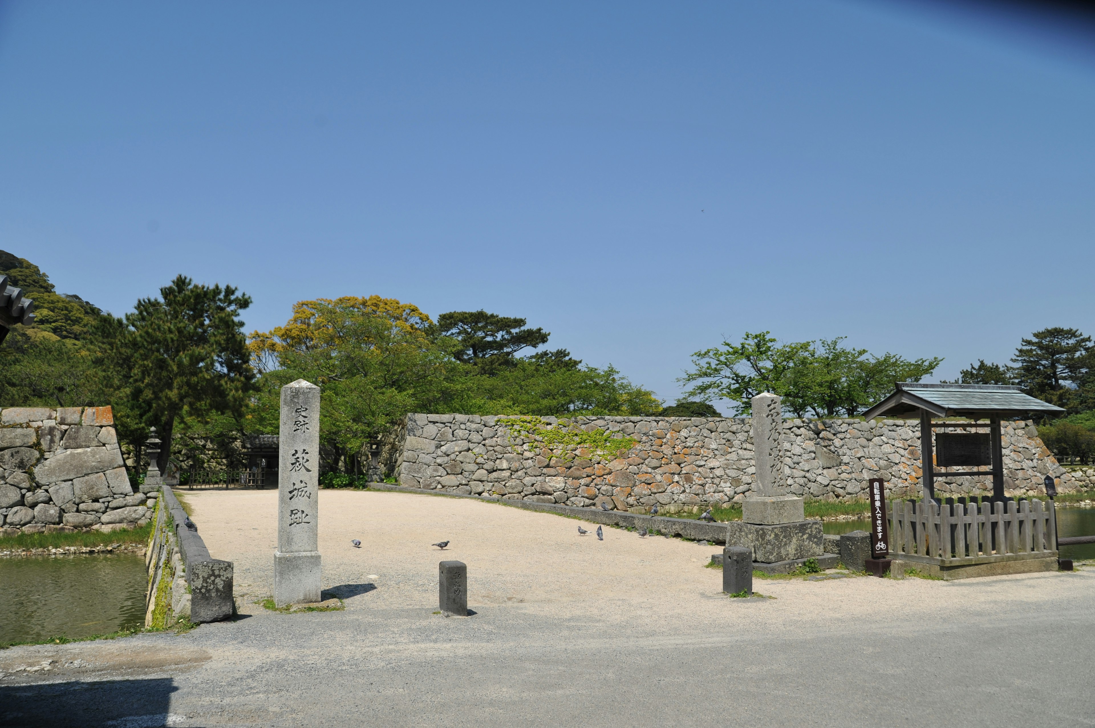 Eingang zu historischen Burgruinen unter blauem Himmel mit Steinmauern und Kiesweg