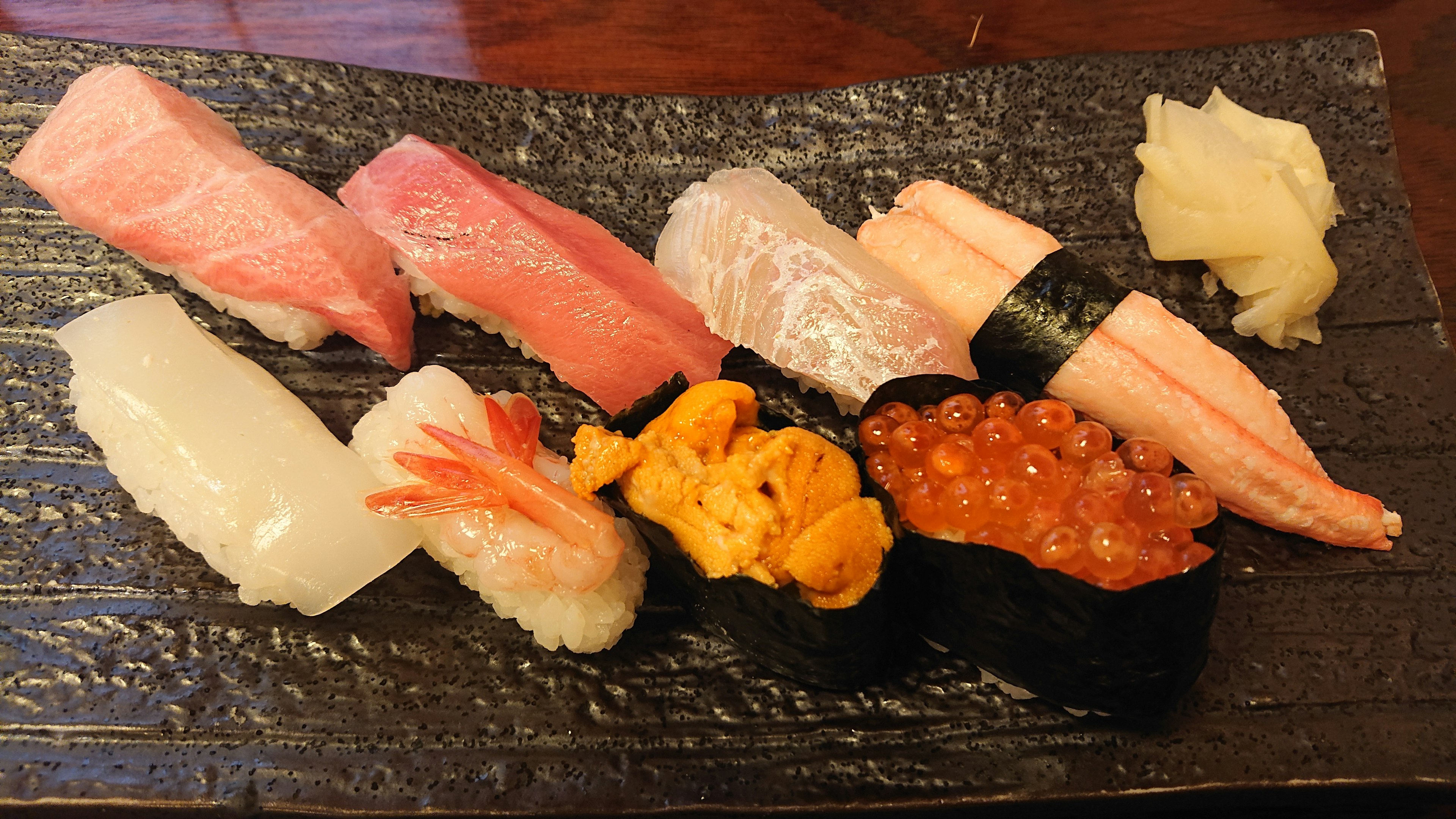 An assortment of colorful sushi displayed on a black plate