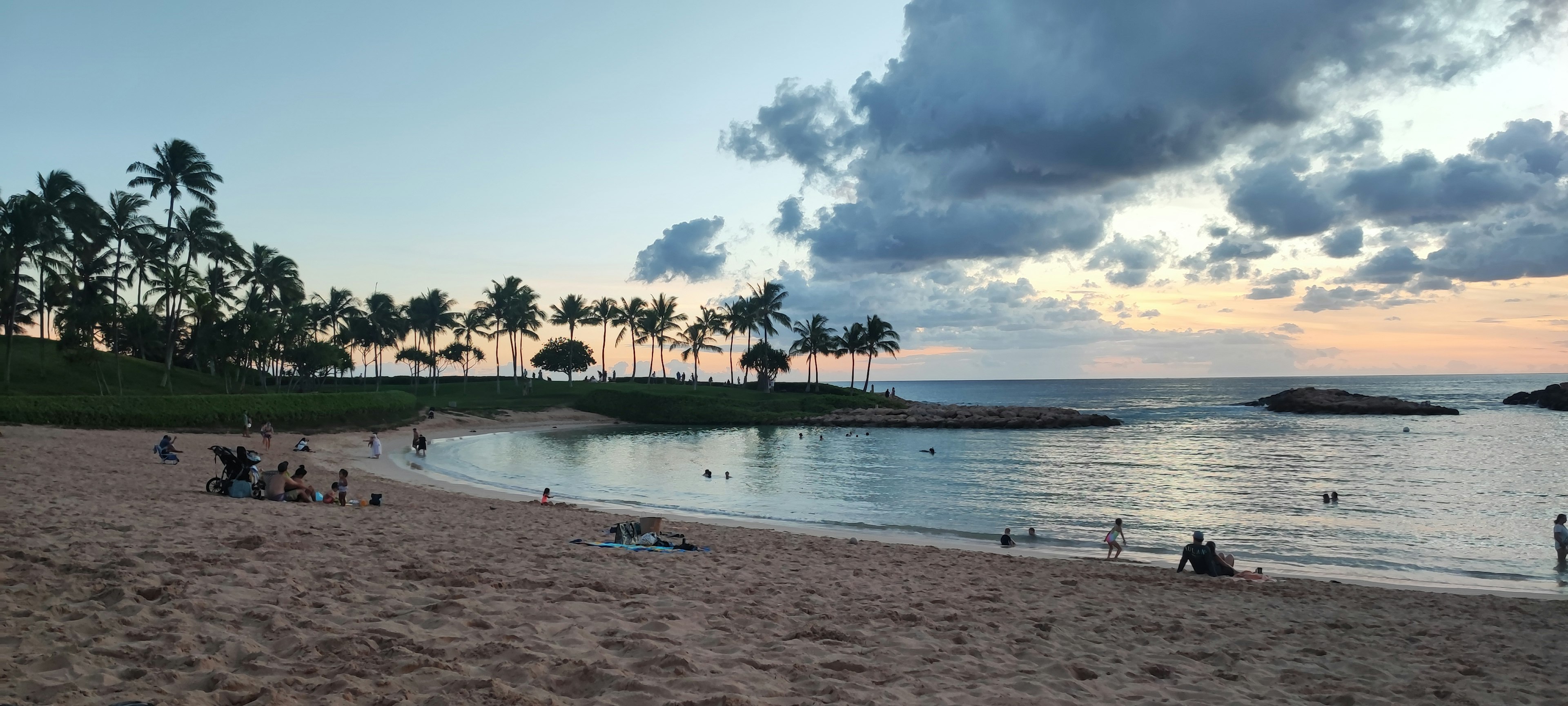 Vista de playa escénica al atardecer con aguas tranquilas y palmeras a lo largo de la costa