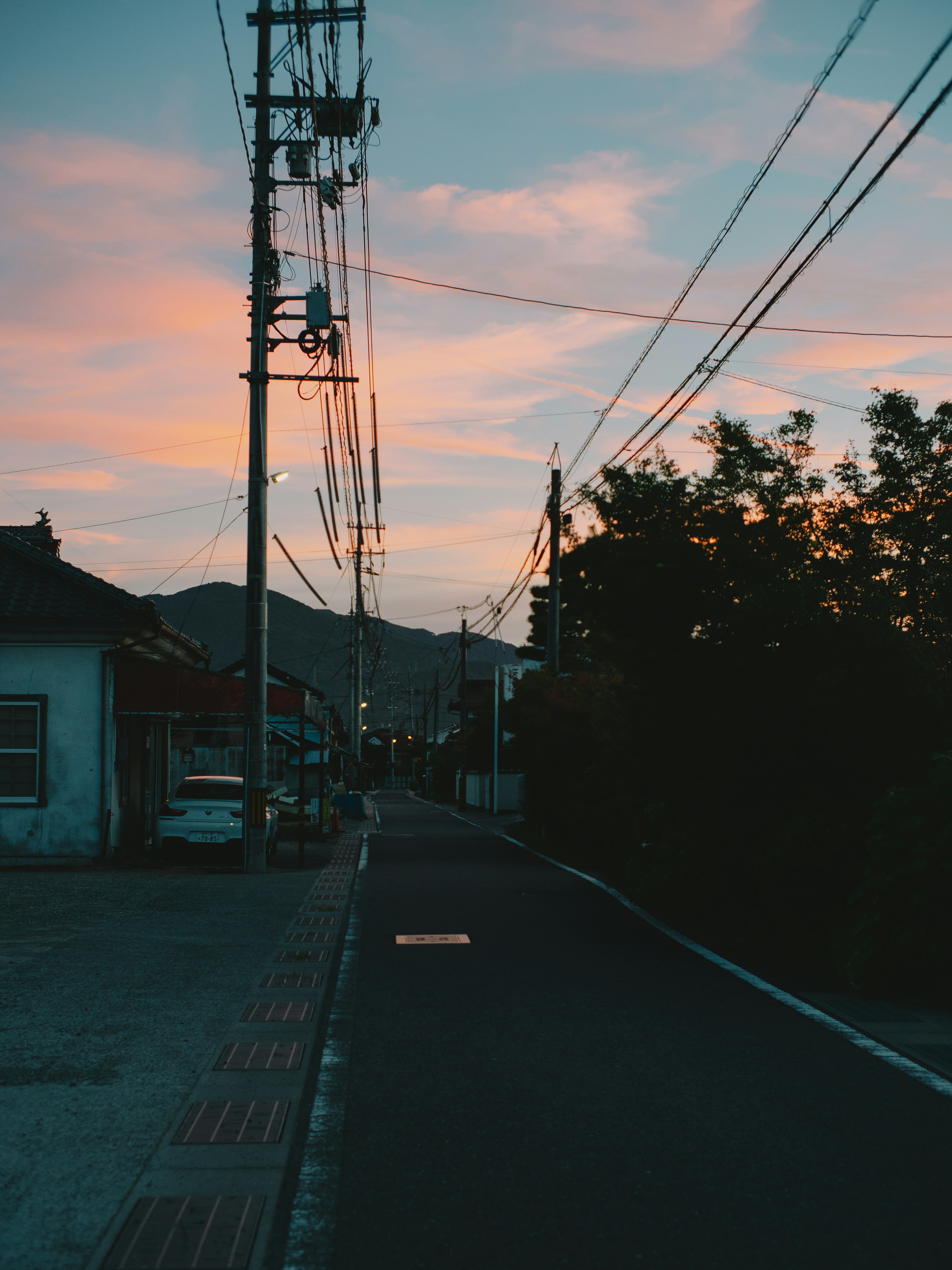 Quiet street with utility poles at dusk and colorful sky