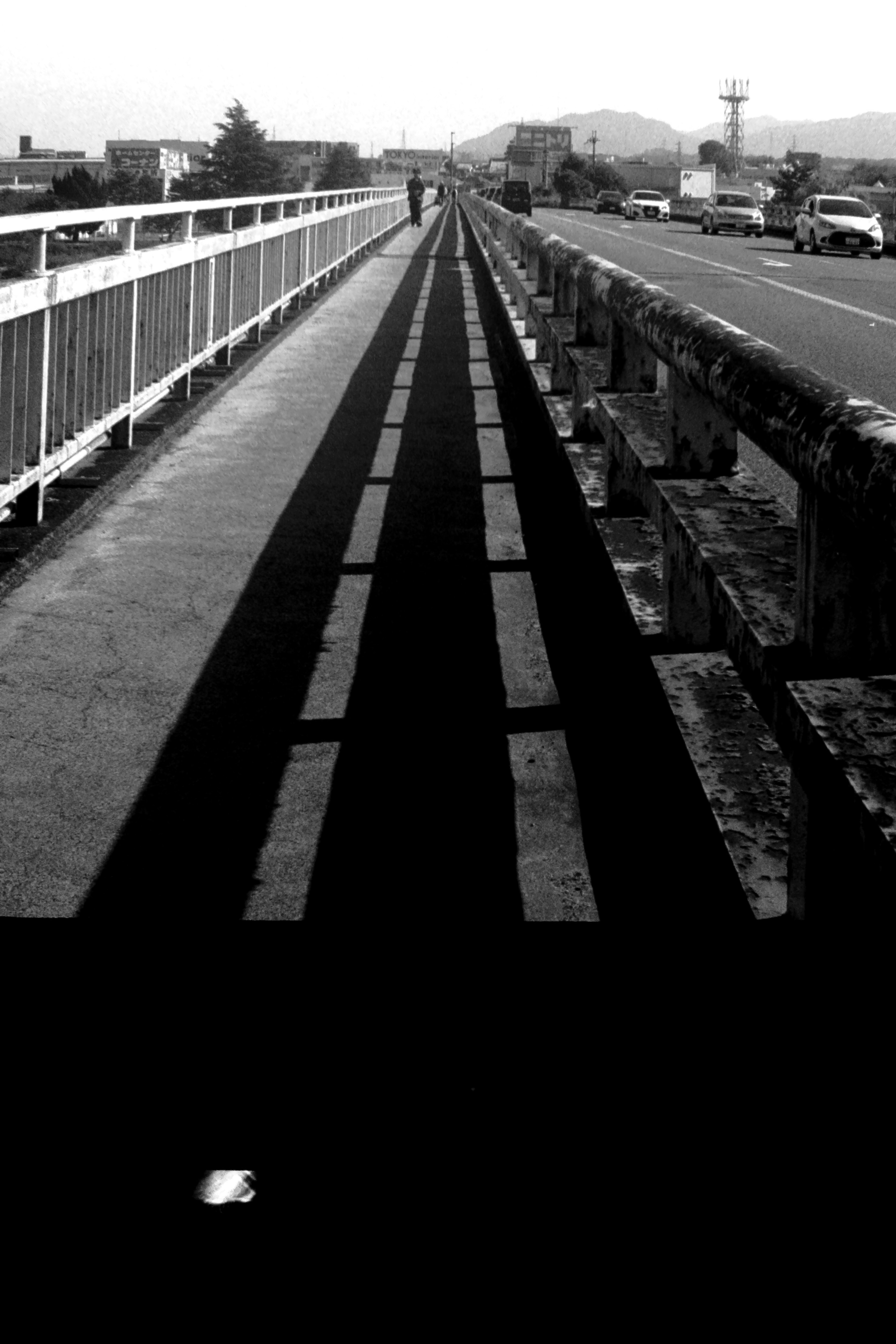 Black and white view of a bridge sidewalk and roadway