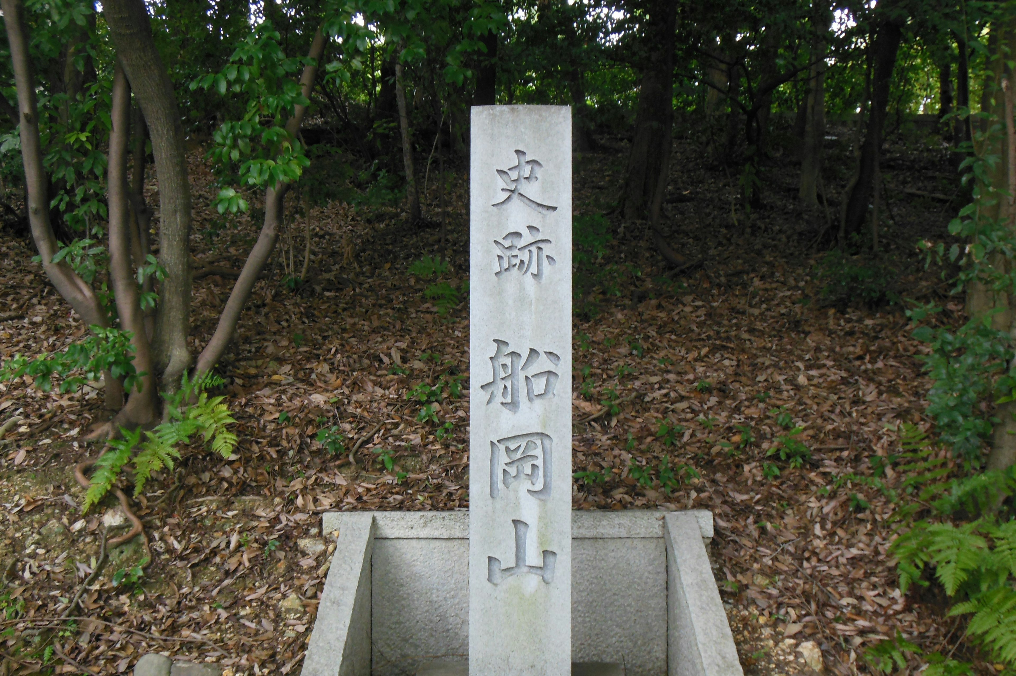 Monumento de piedra blanca en un bosque con la inscripción Bunshin Funakoyama