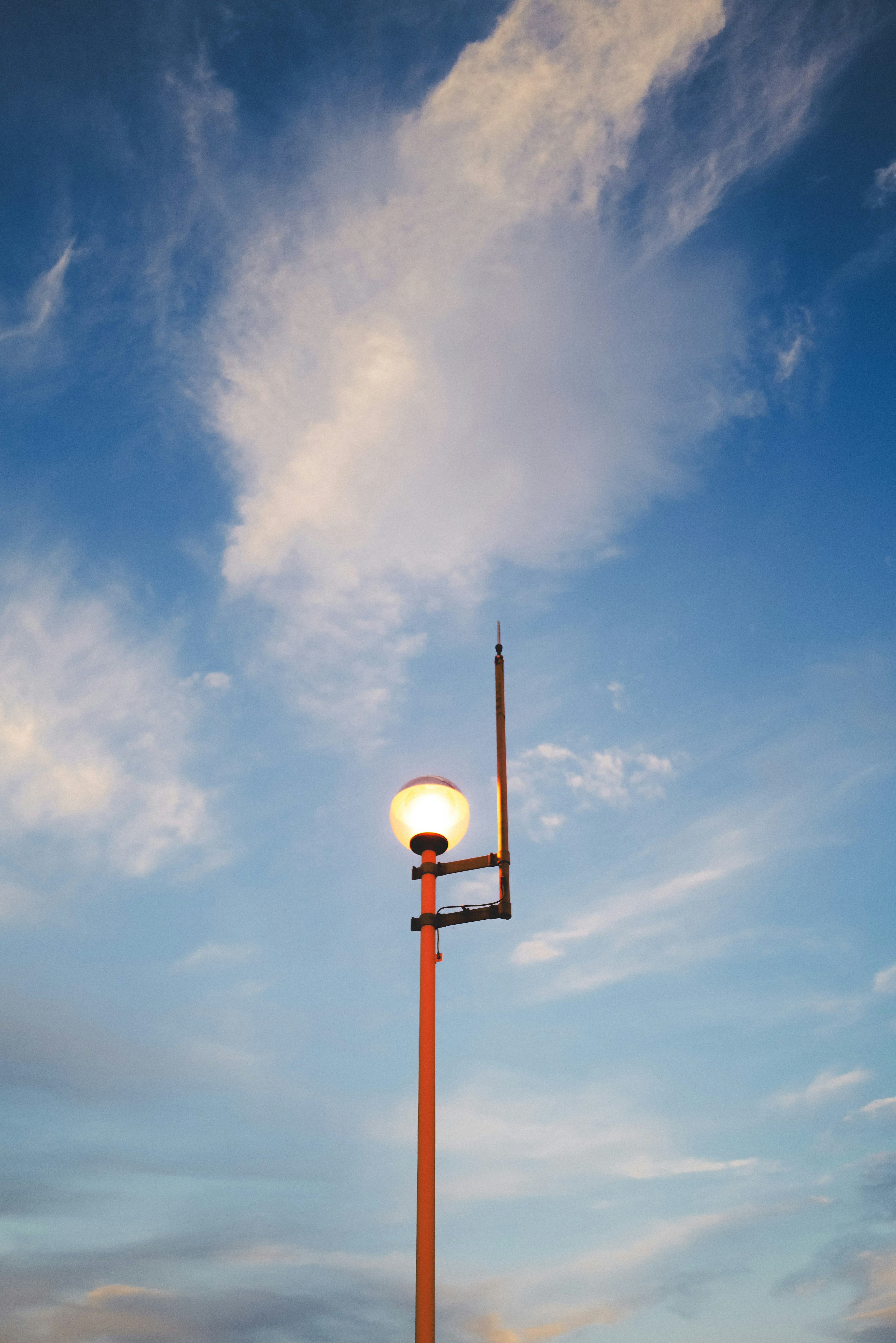 Farola de pie contra un cielo azul con nubes esponjosas