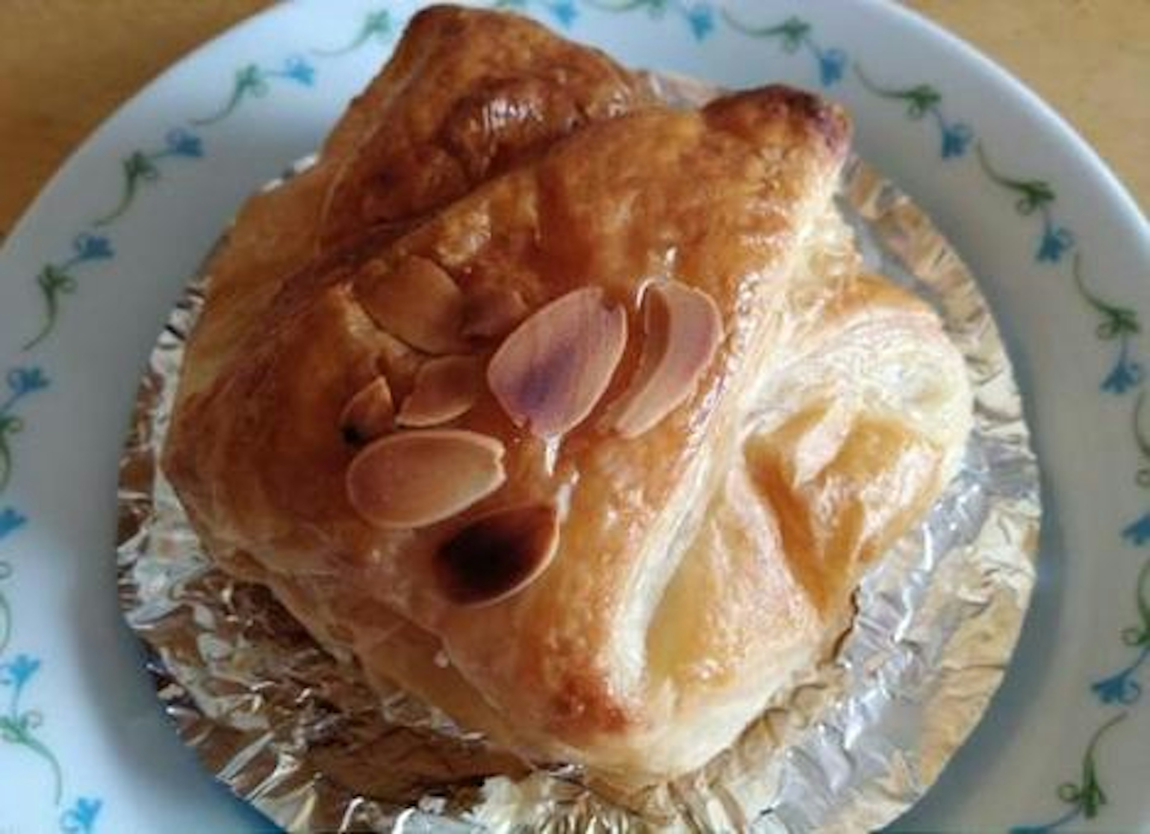 Pastry topped with almond slices on a decorative plate