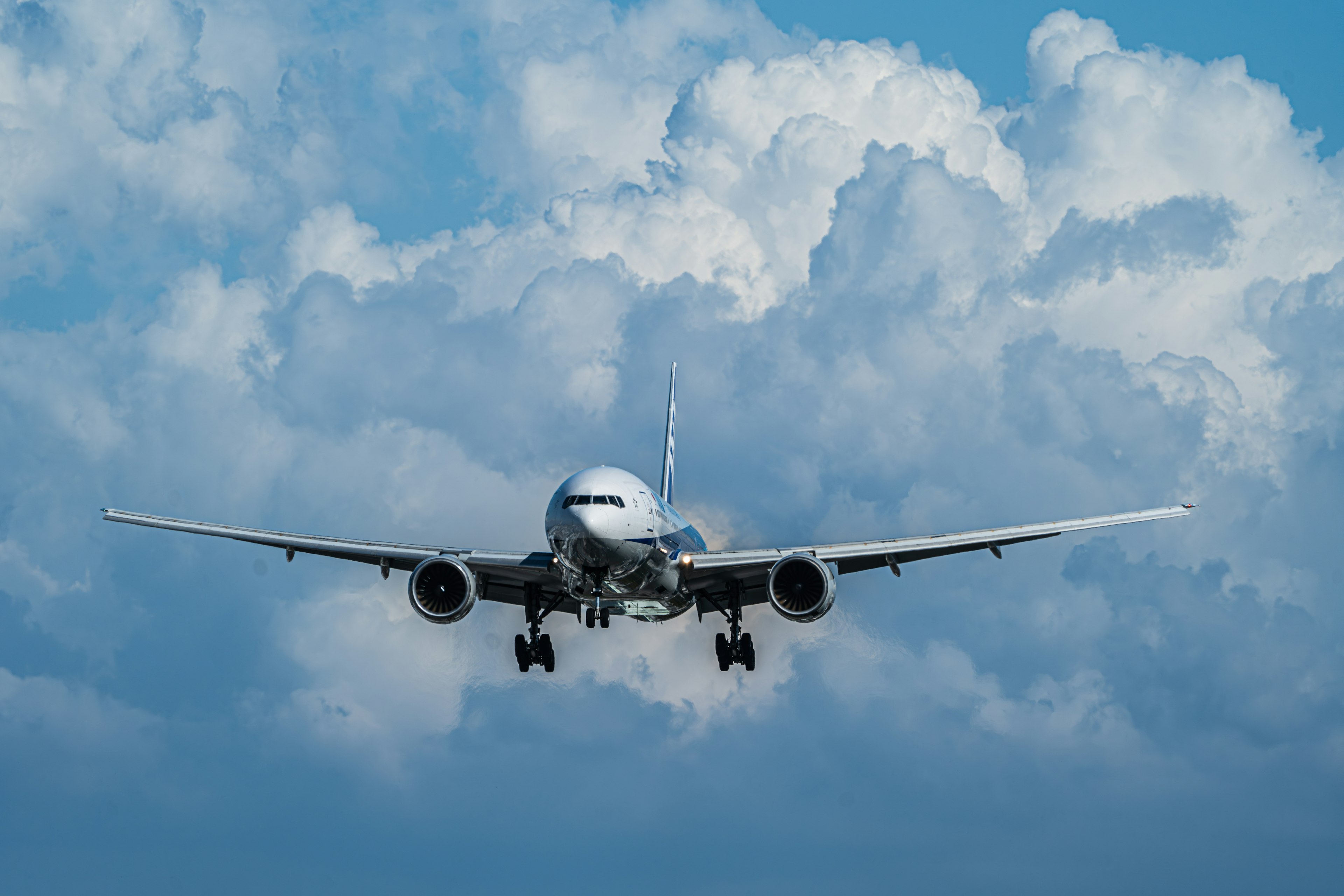 青空と白い雲の中を飛行機が着陸するシーン