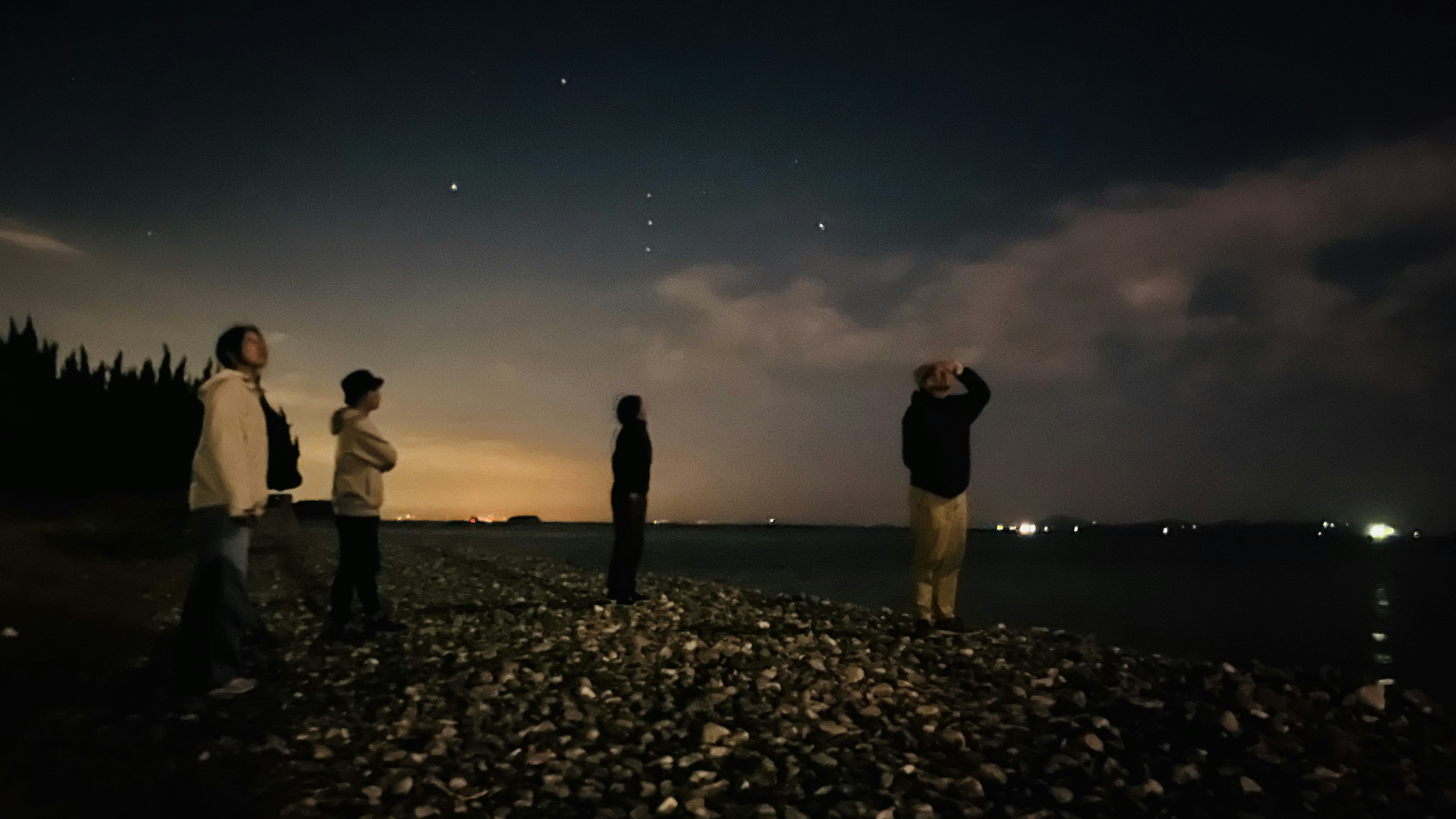 夜空を見上げる人々のシルエットと星々の光