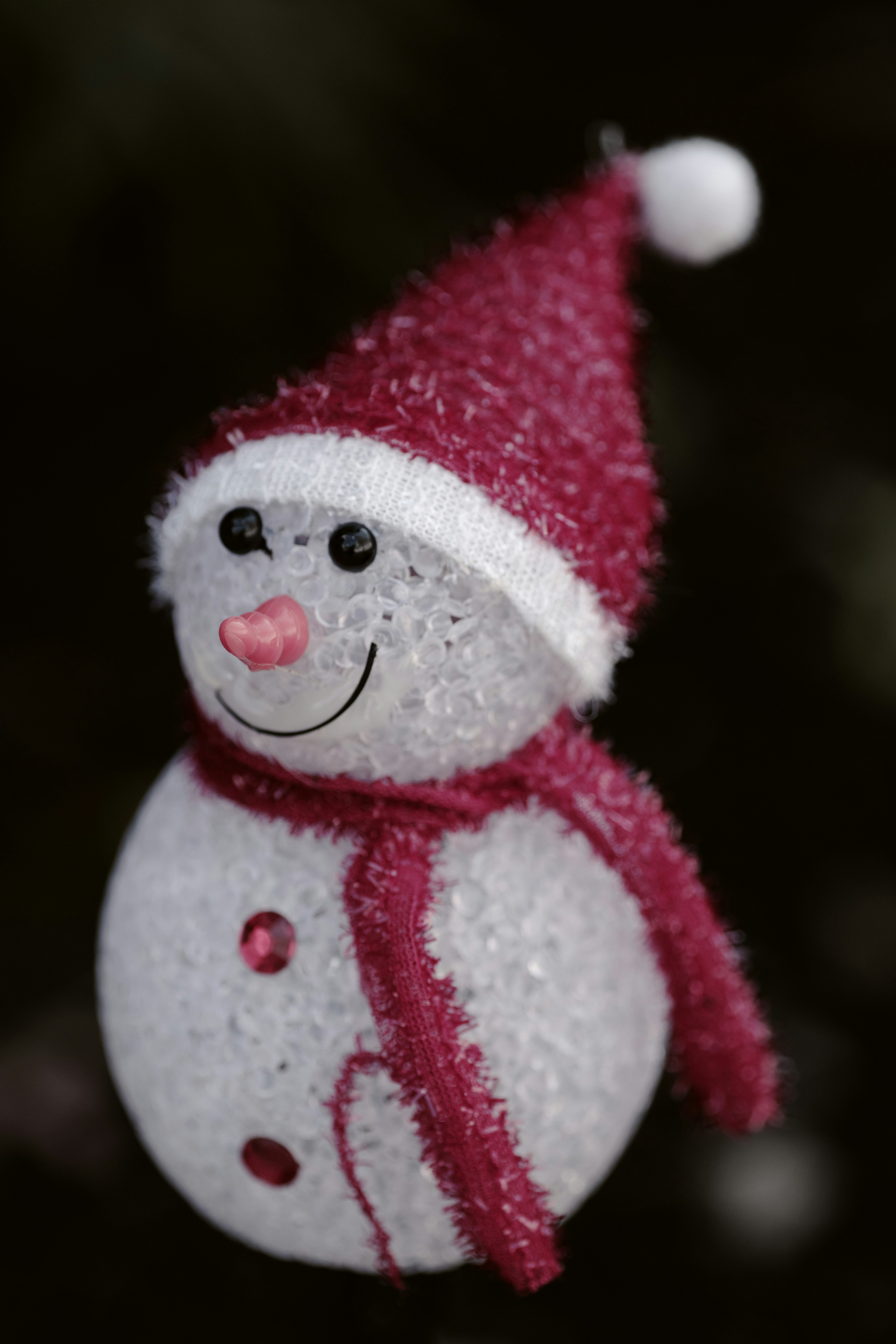 A cute snowman ornament wearing a red hat and scarf